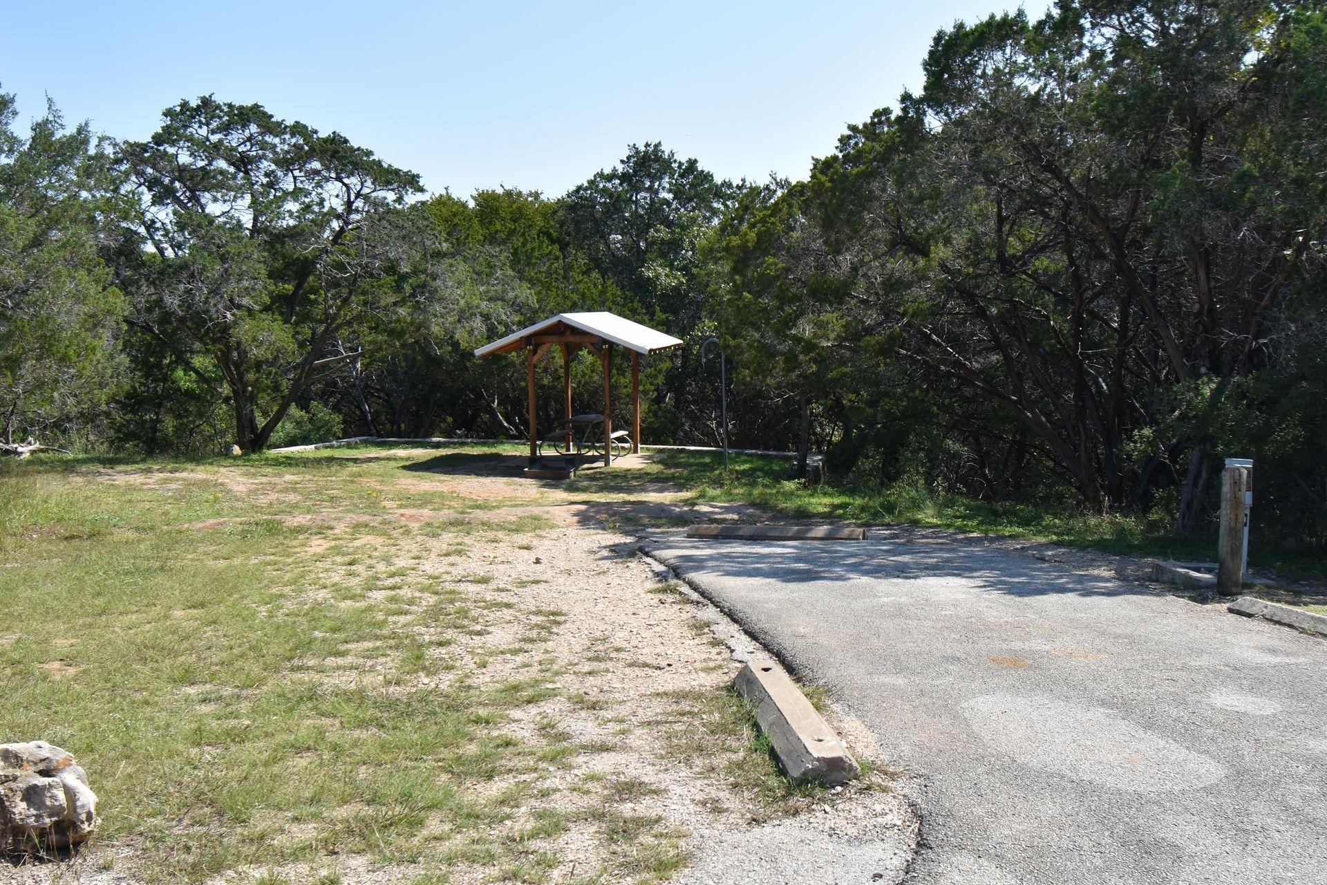 A campsite in Pedernales Falls with a shelter and forest in the background