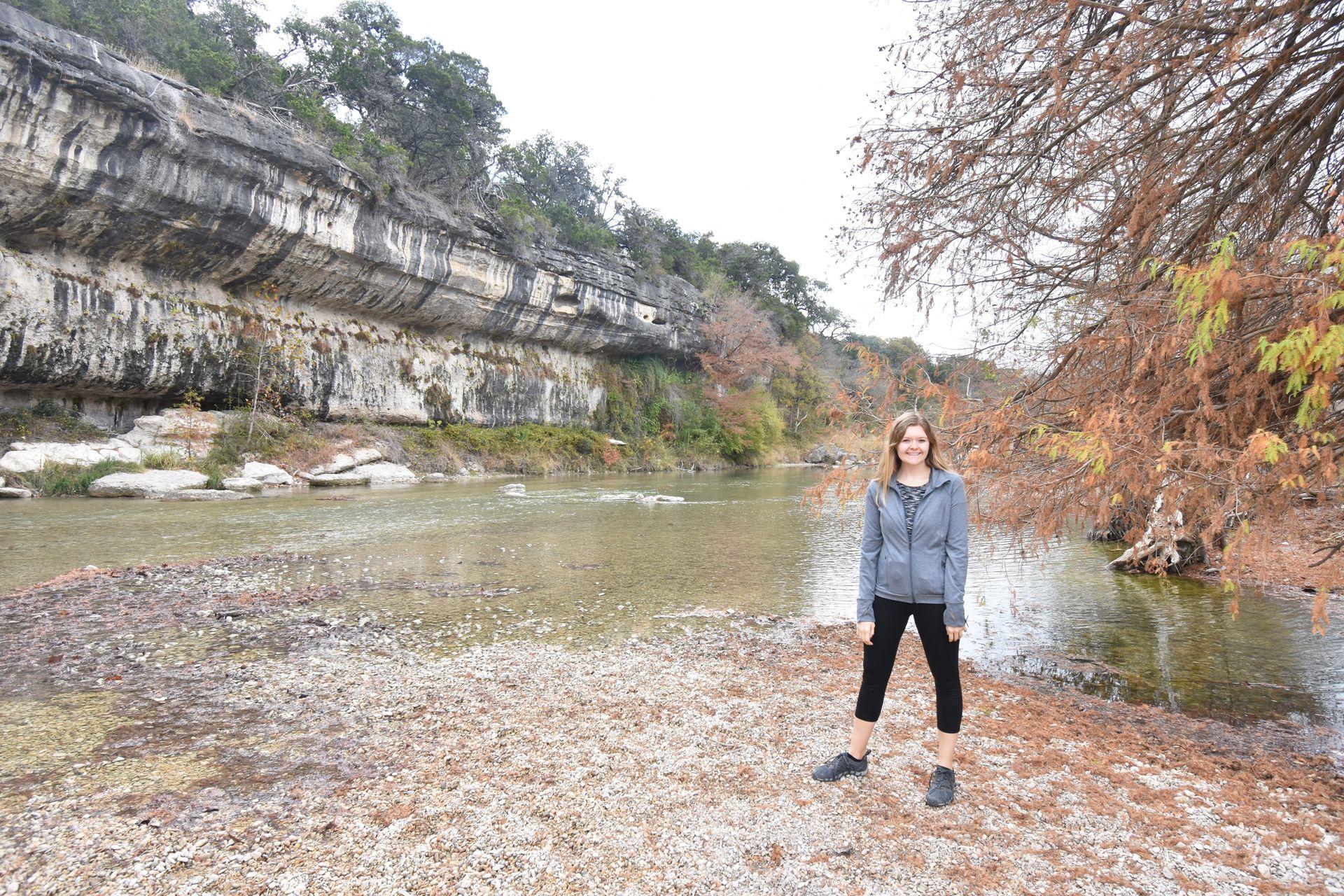 Lydia standing on an edge of the Guadalupe River.