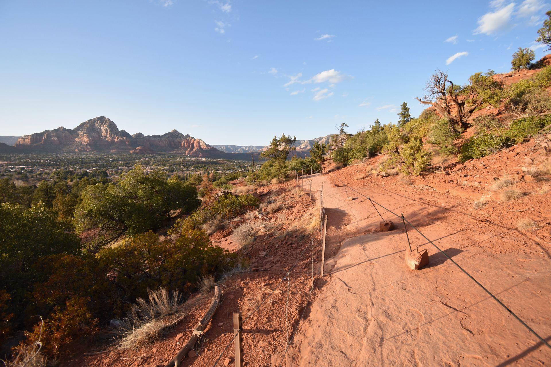 A trail with a railing and a mountain in the background.