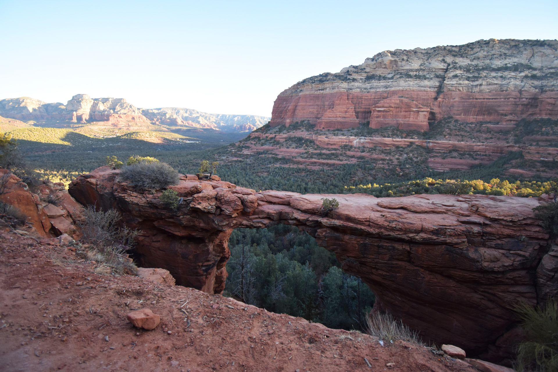 Looking out at Devil's Bridge, a giant red rock bridge. There is a mesa in the background.