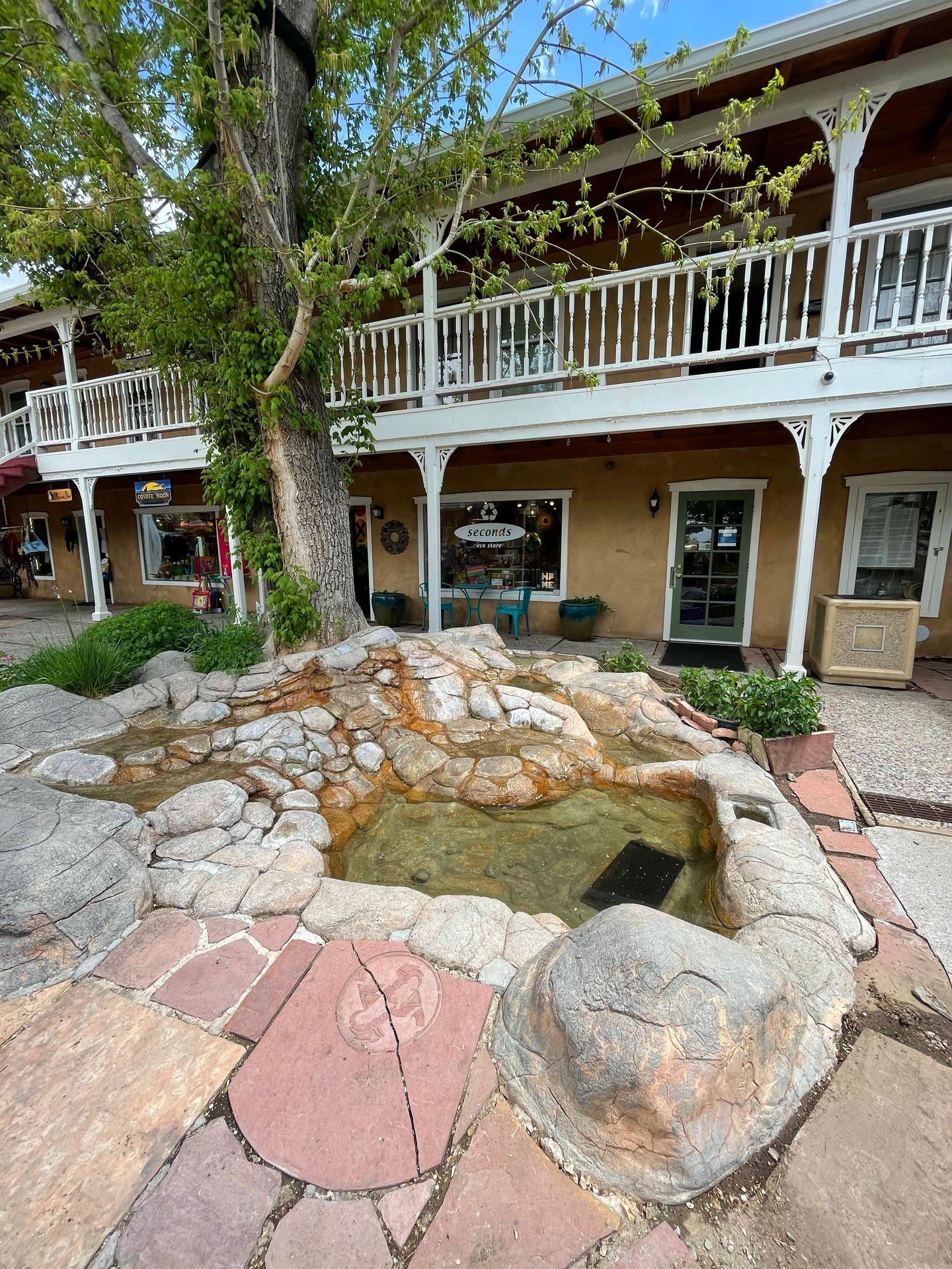 Two levels of businesses with some rock landscaping a small pond in front.