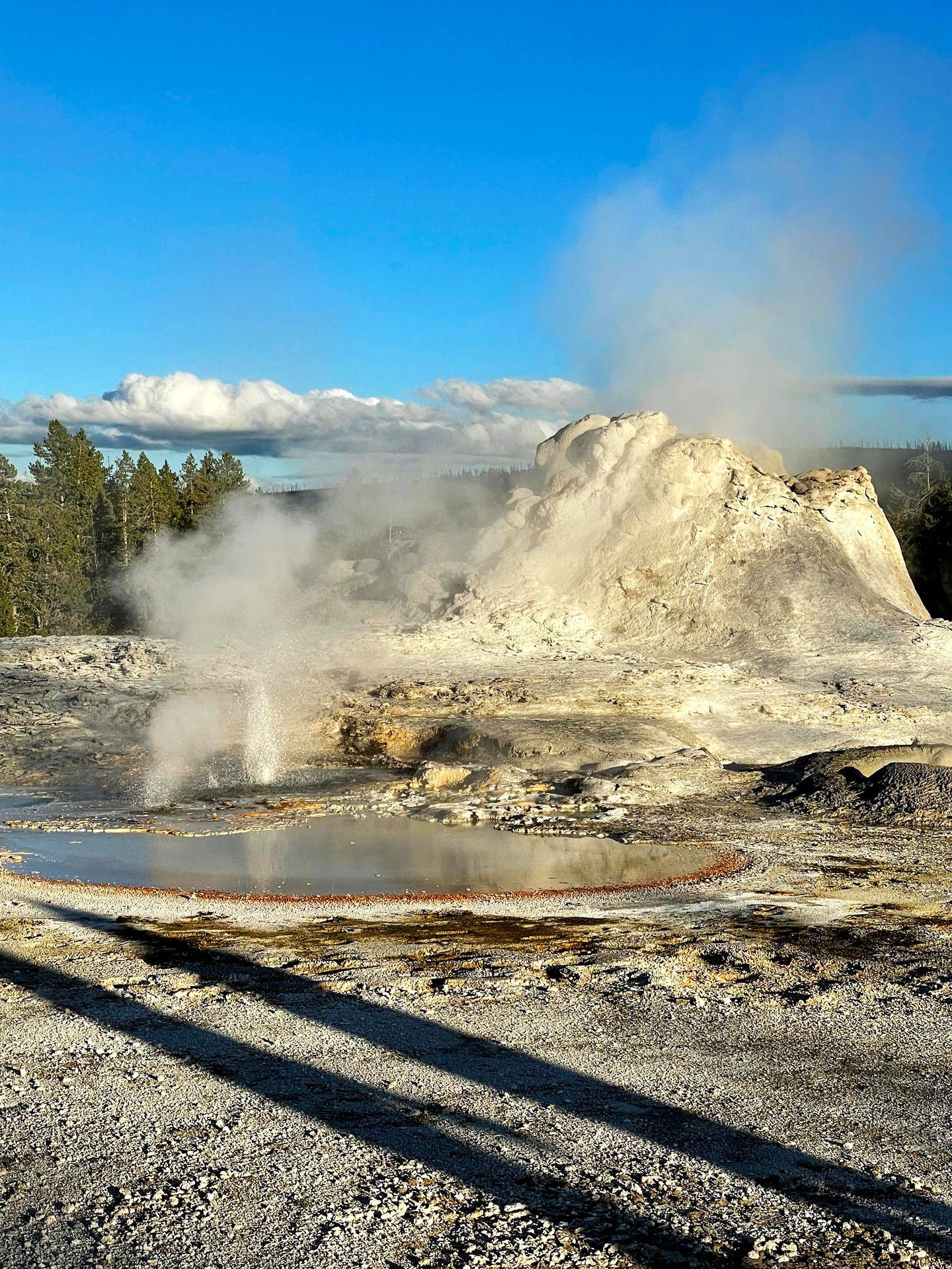 A view of the Castle Geyser with a hot spring steaming next to it.
