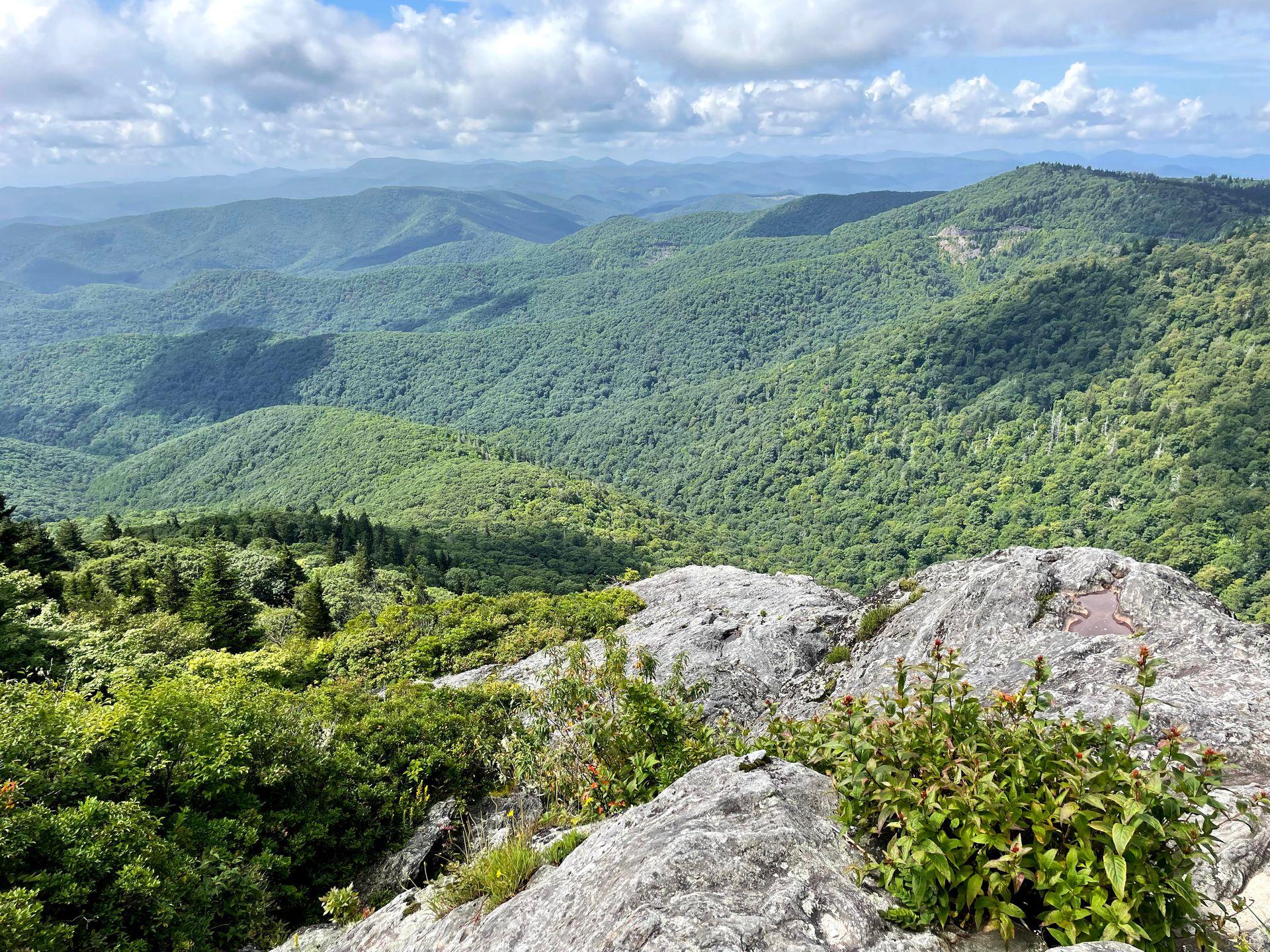 An expansive view of mountains covered in green trees from the Devil's Courthouse trail.