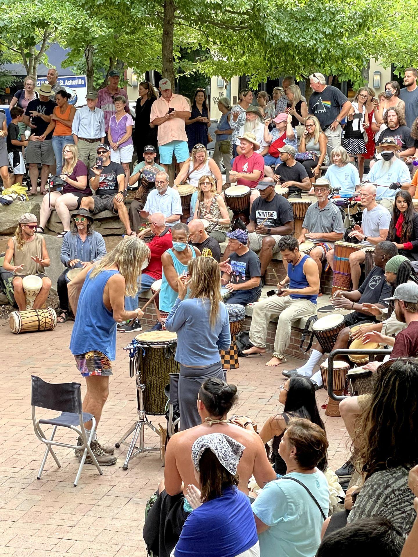 Several people playing drums together in Pritchard Park.