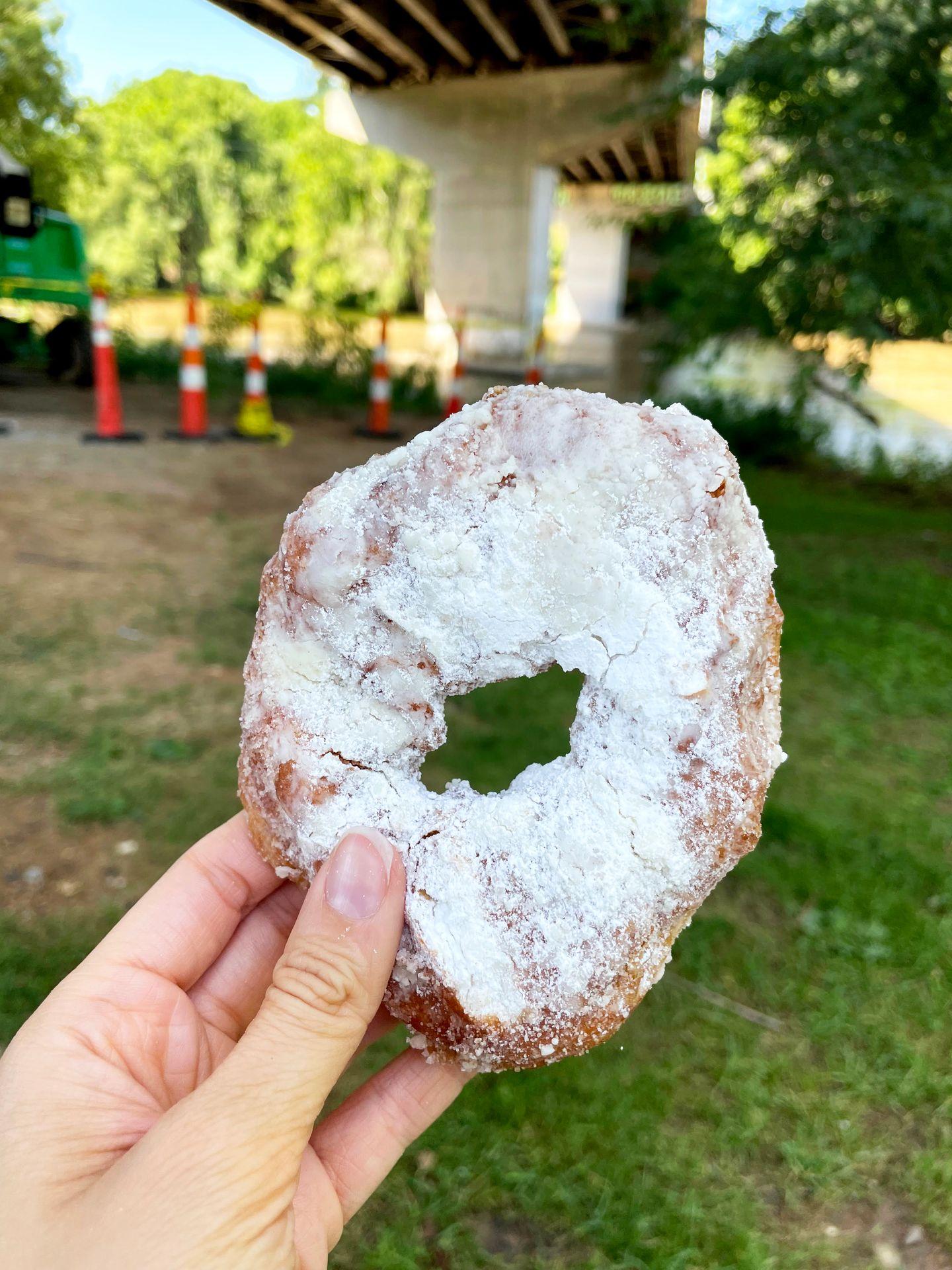 Holding up a powdered sugar donut from Hole Doughnuts.