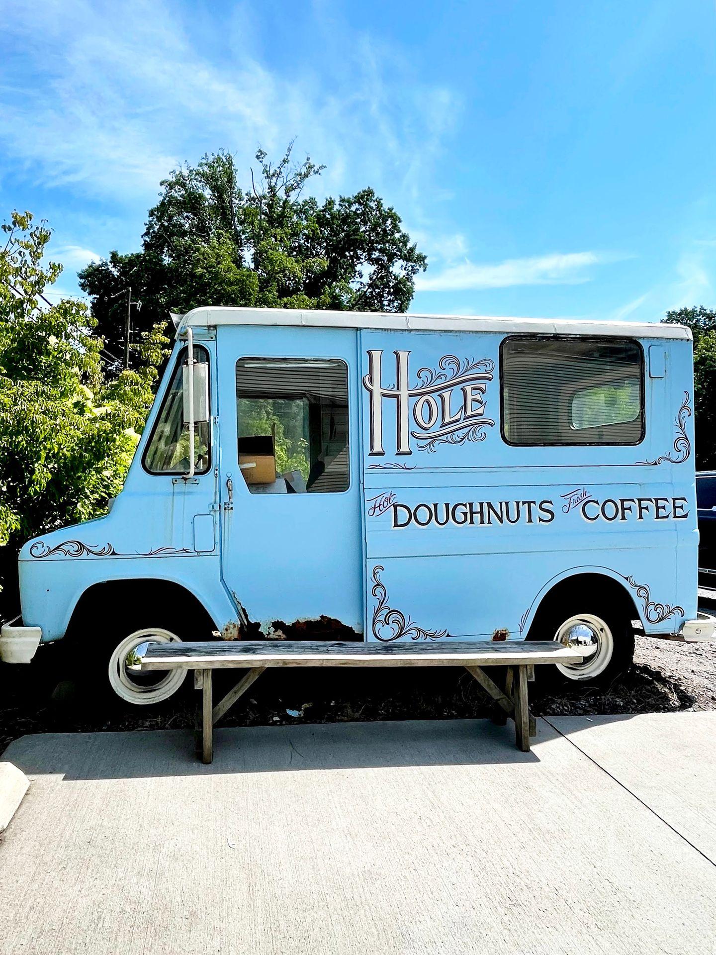 A small blue food truck that reads Hole: Doughnuts and Coffee