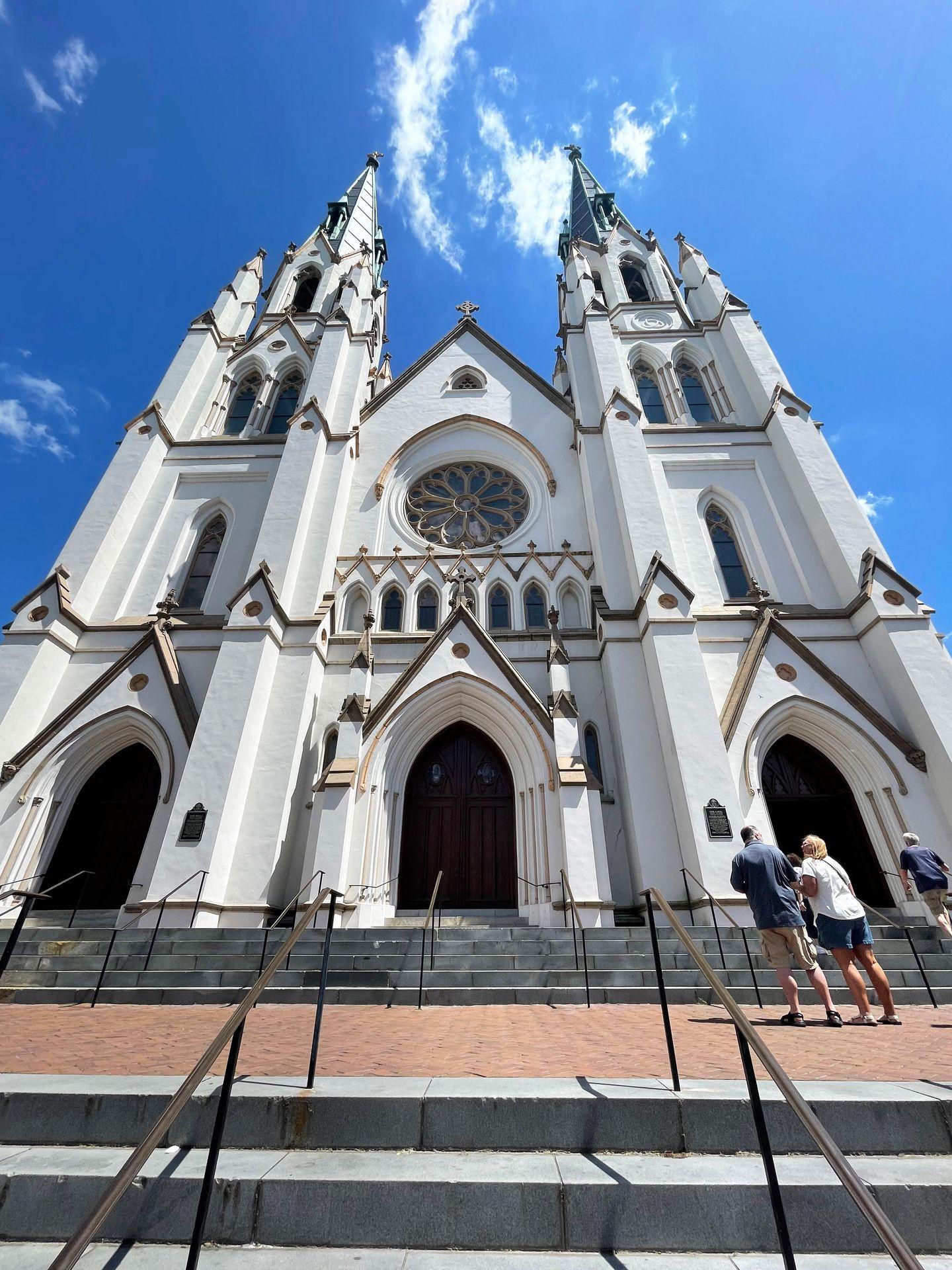 Looking up at the Cathedral Basilica, a large white church in downtown Savannah.