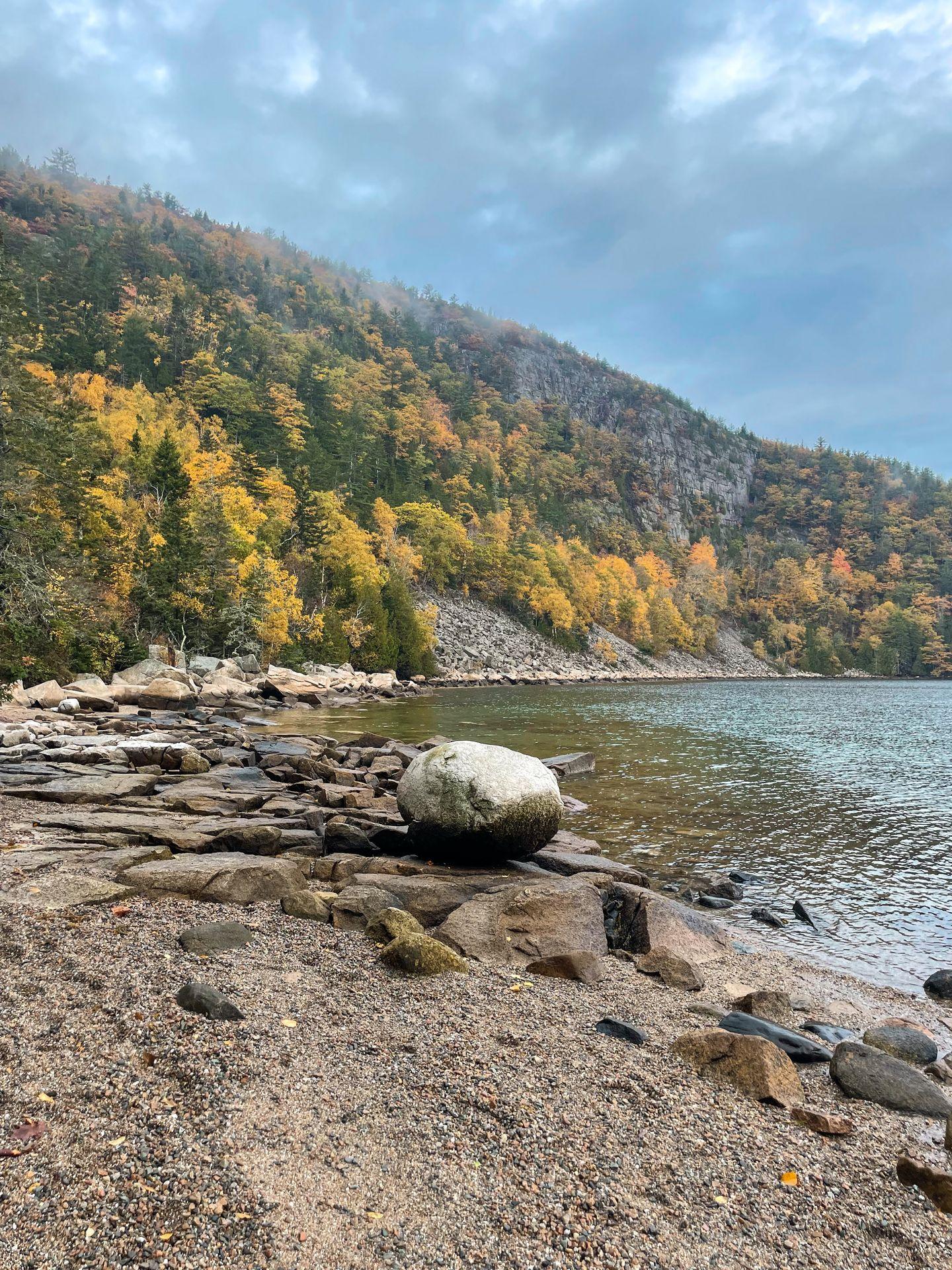 A boulder sitting along the shore of a beach.