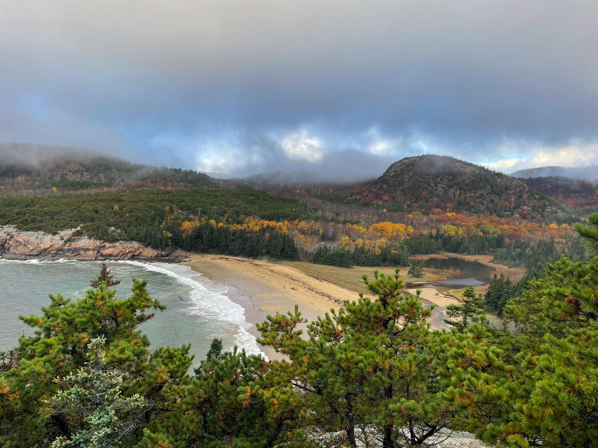 Looking down at Sand Beach from the Great Head Trail. In the background, the Beehive is covered in fall foliage.