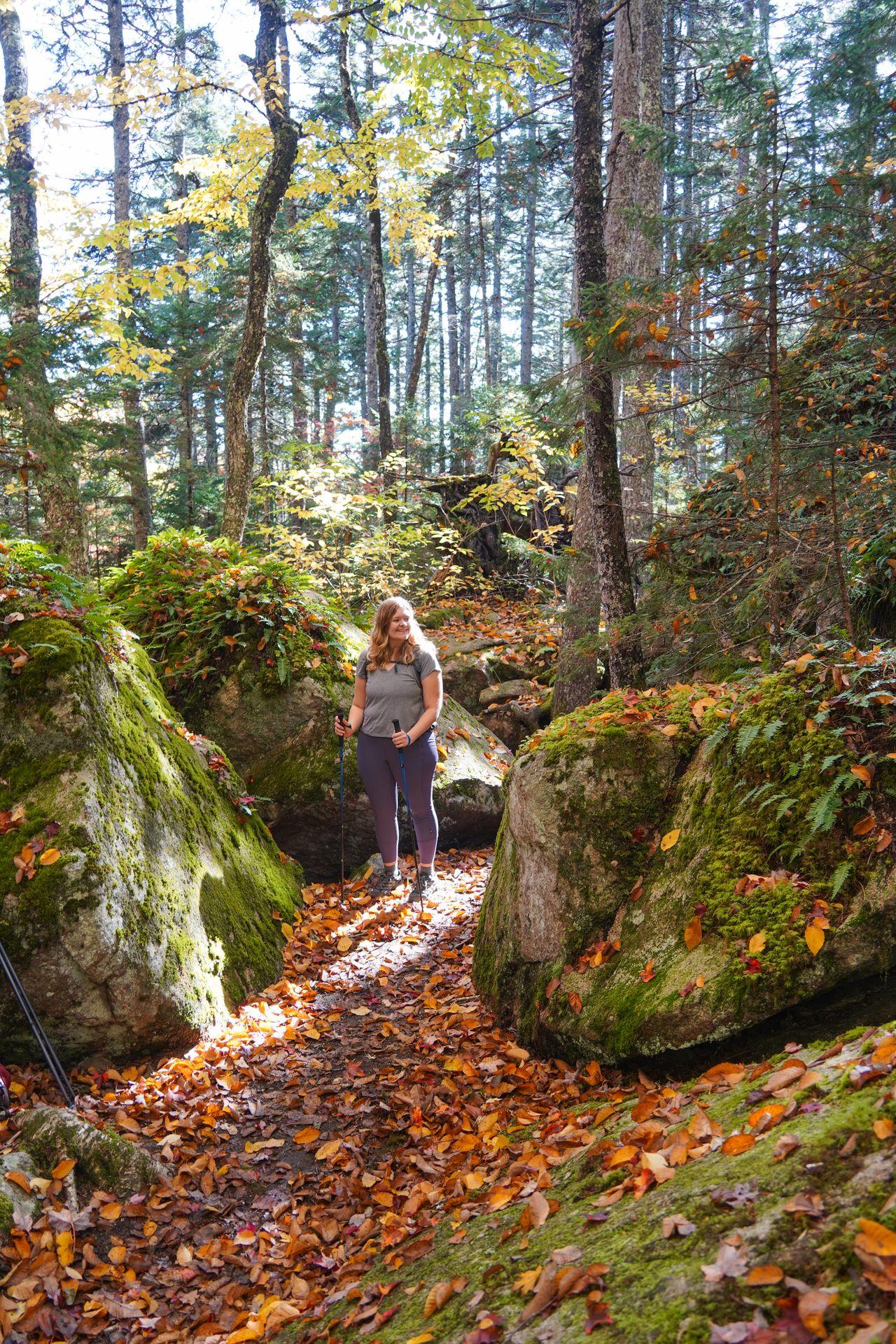 Lydia standing on the Beech Mountain South Ridge Loop trail surrounded by moss-covered boulders.