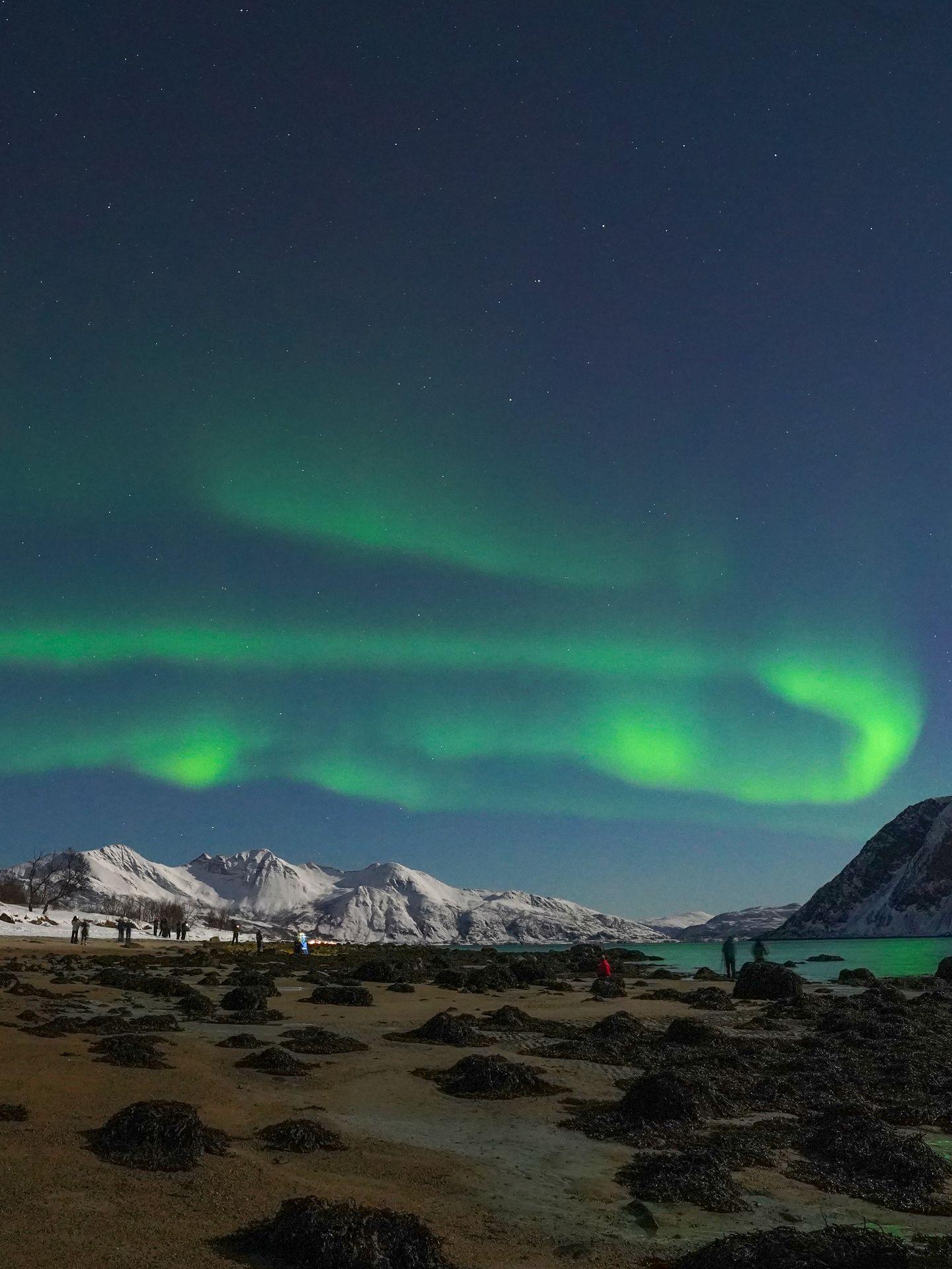 Aurora Borealis in the sky, with snow capped mountains below