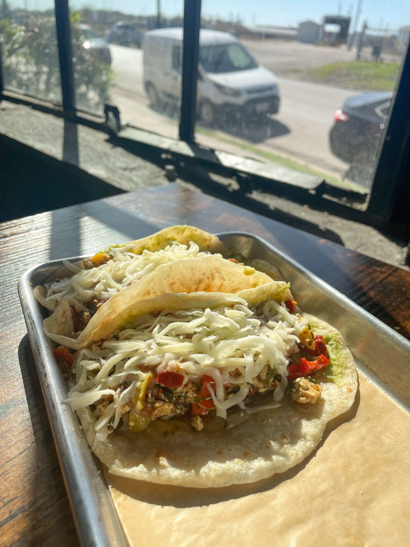 Two tacos with cheese, veggies and more from Segundo Coffee Lab