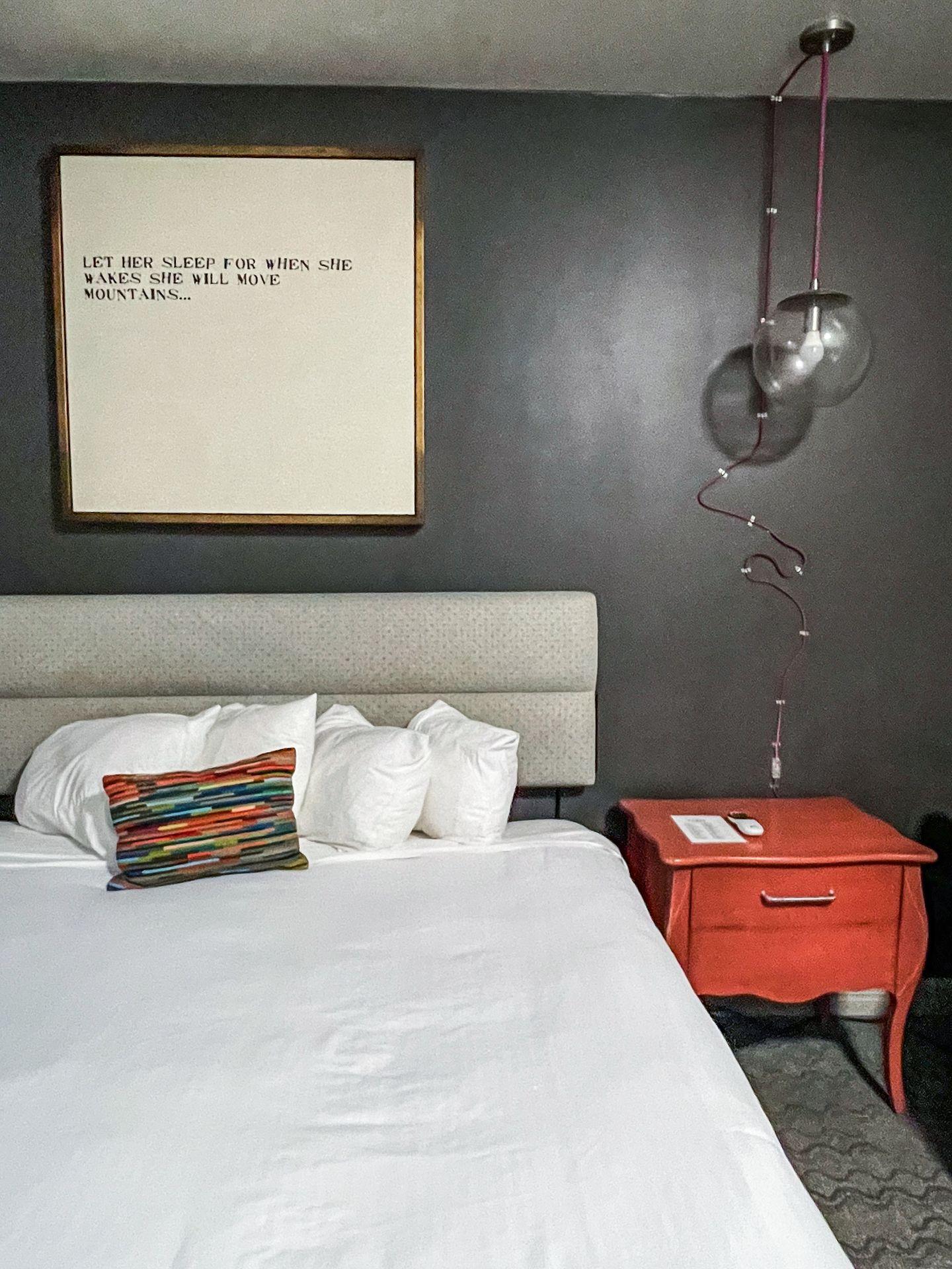 A bed next to a bright orange night stand in Hotel Ylem
