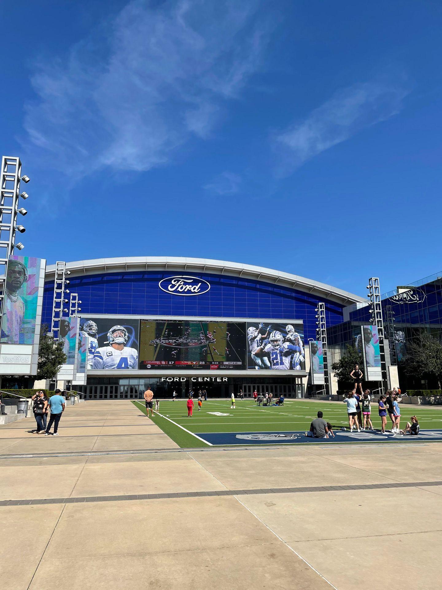 The outdoor area of the Cowboys practice facility at the Frisco Star. There is a football field and a giant tv.