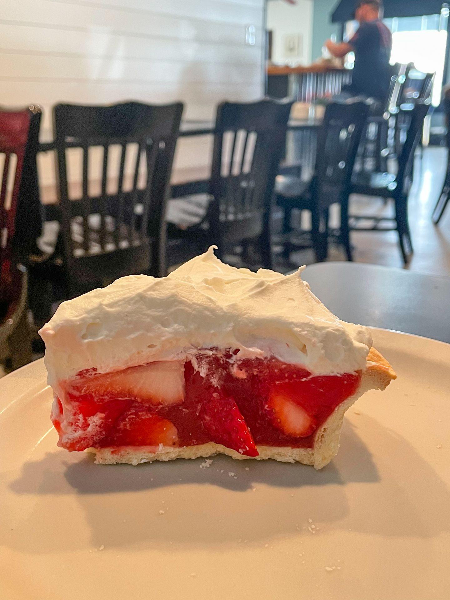 A tall slice of strawberry pie topped with whipped cream.