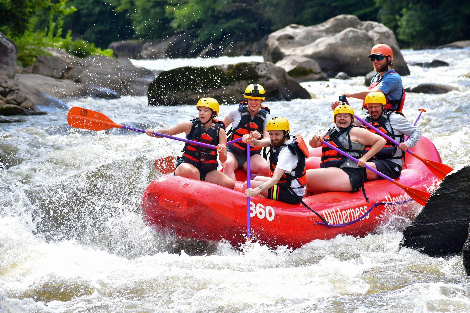 Lydia and 5 others on a whitewater rafting trip in Ohiopyle. The rafting is going down a small waterfall.