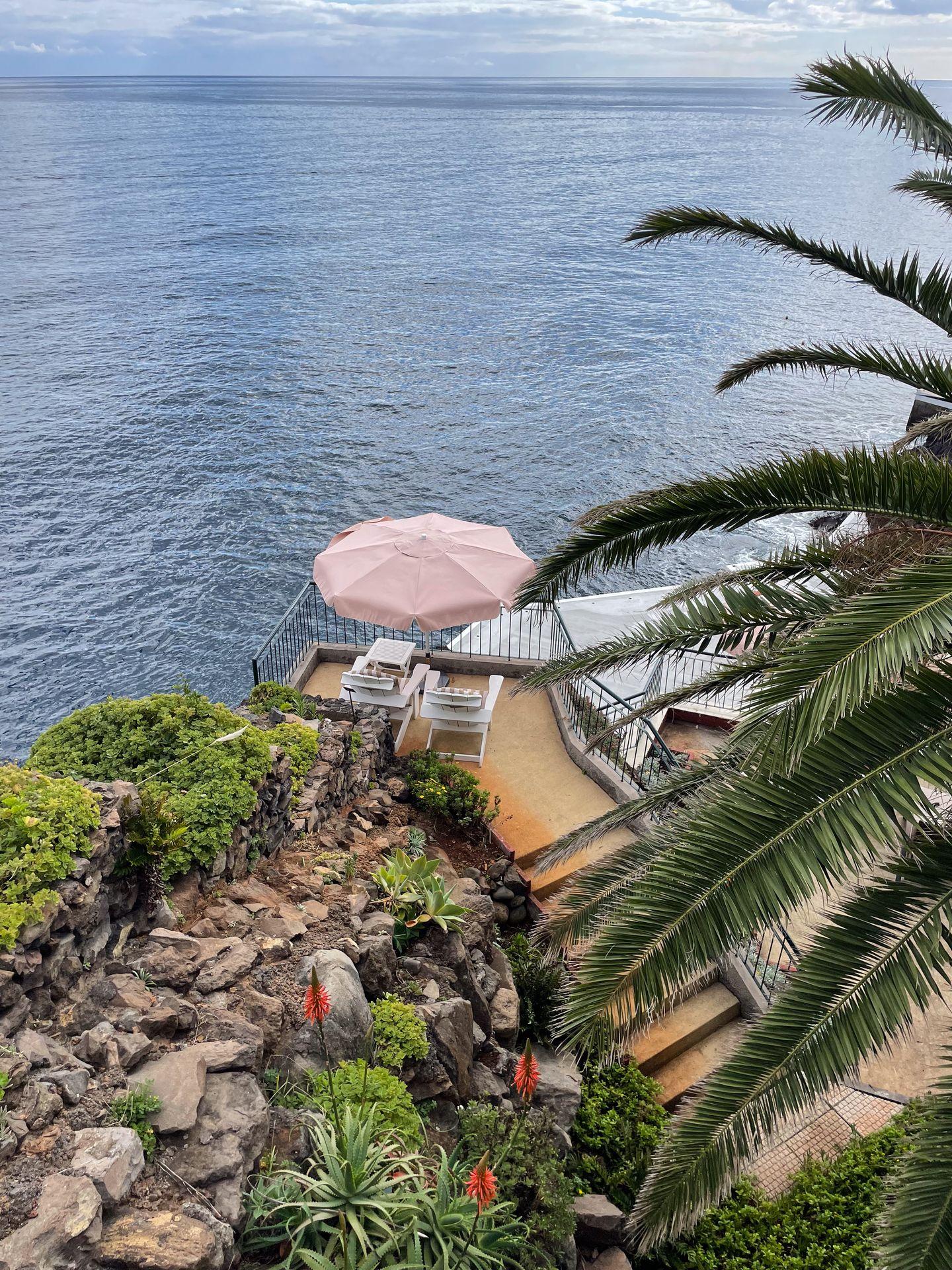 Two pool chairs under an umbrella in a secluded and tucked away area at the Cliff Bay Hotel