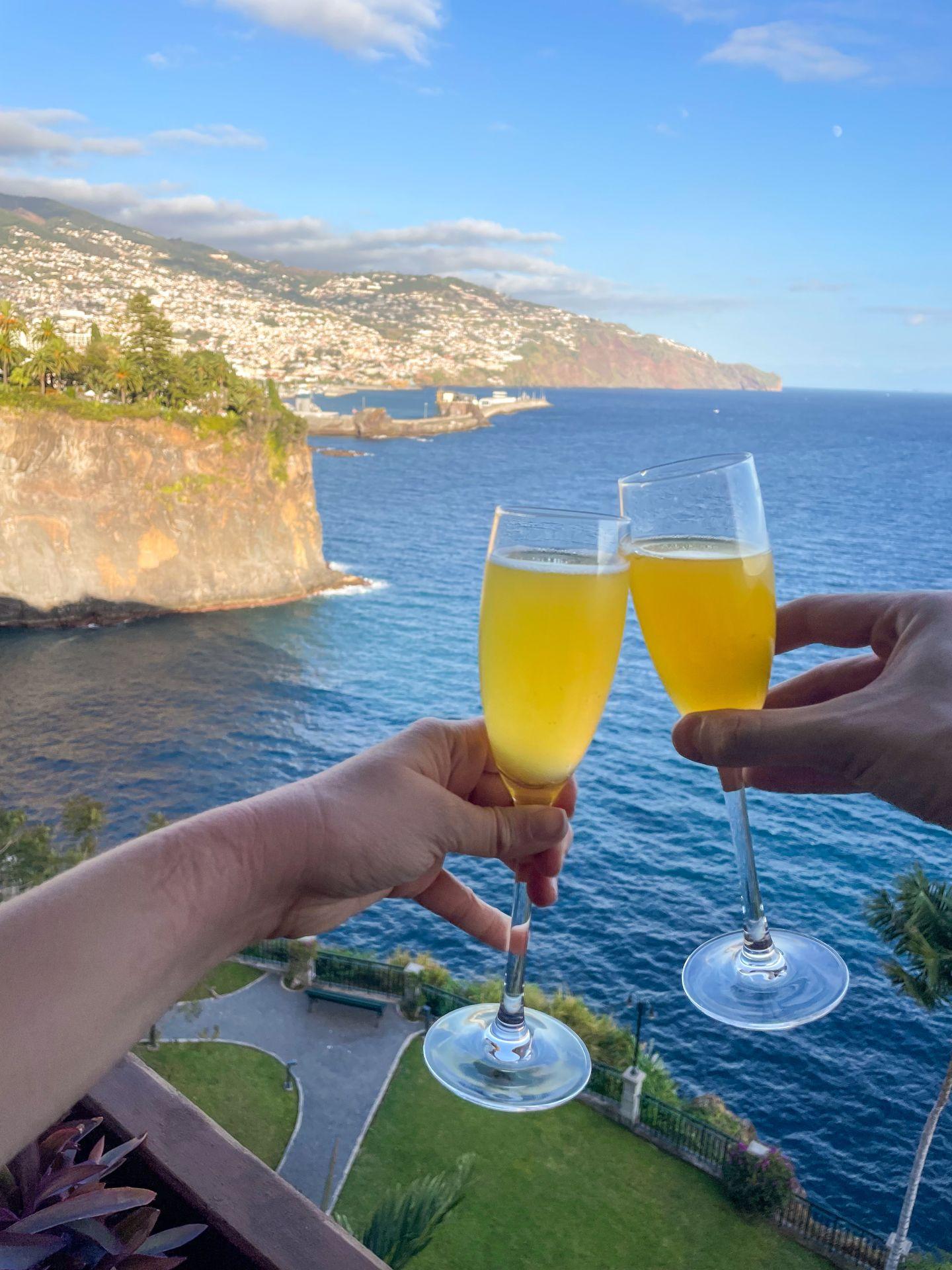 A cheers with two glasses of passion fruit juice on a balcony of the Cliff Bay Hotel