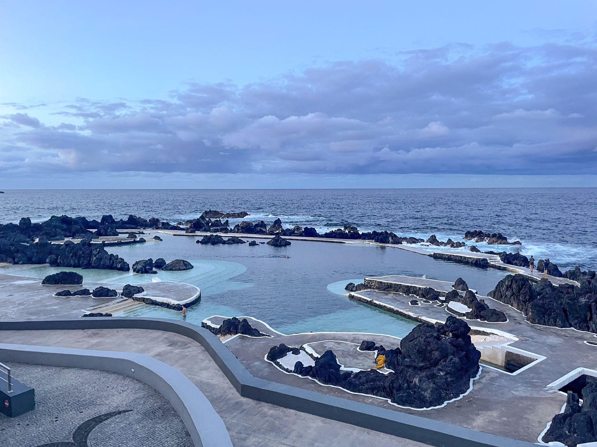 A swimming area surrounded by patches of black, volcanic rocks