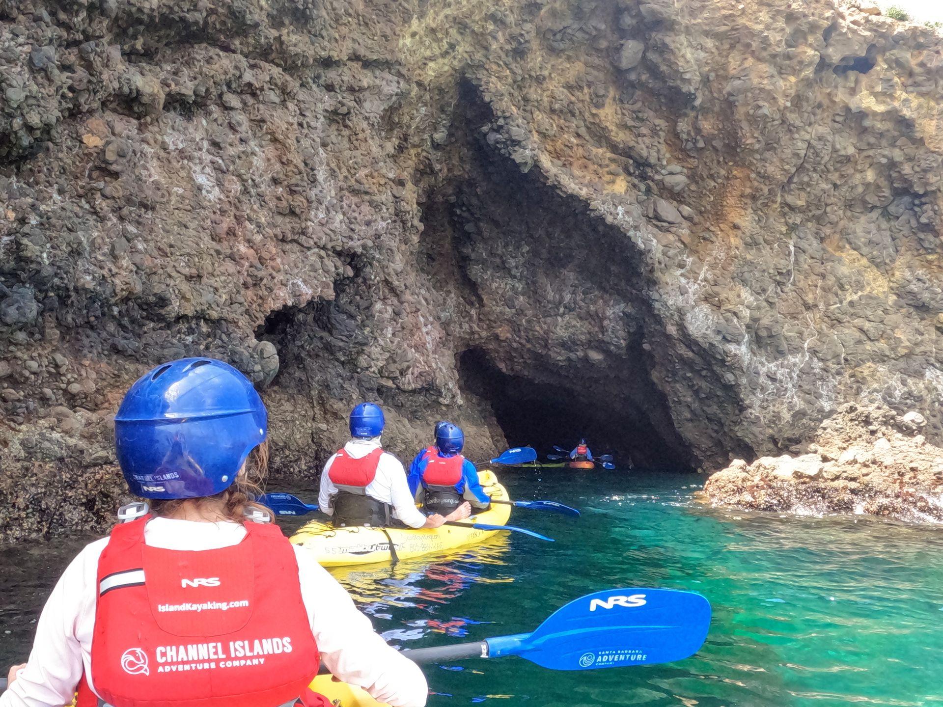 A line of kayaks heading into a sea cave