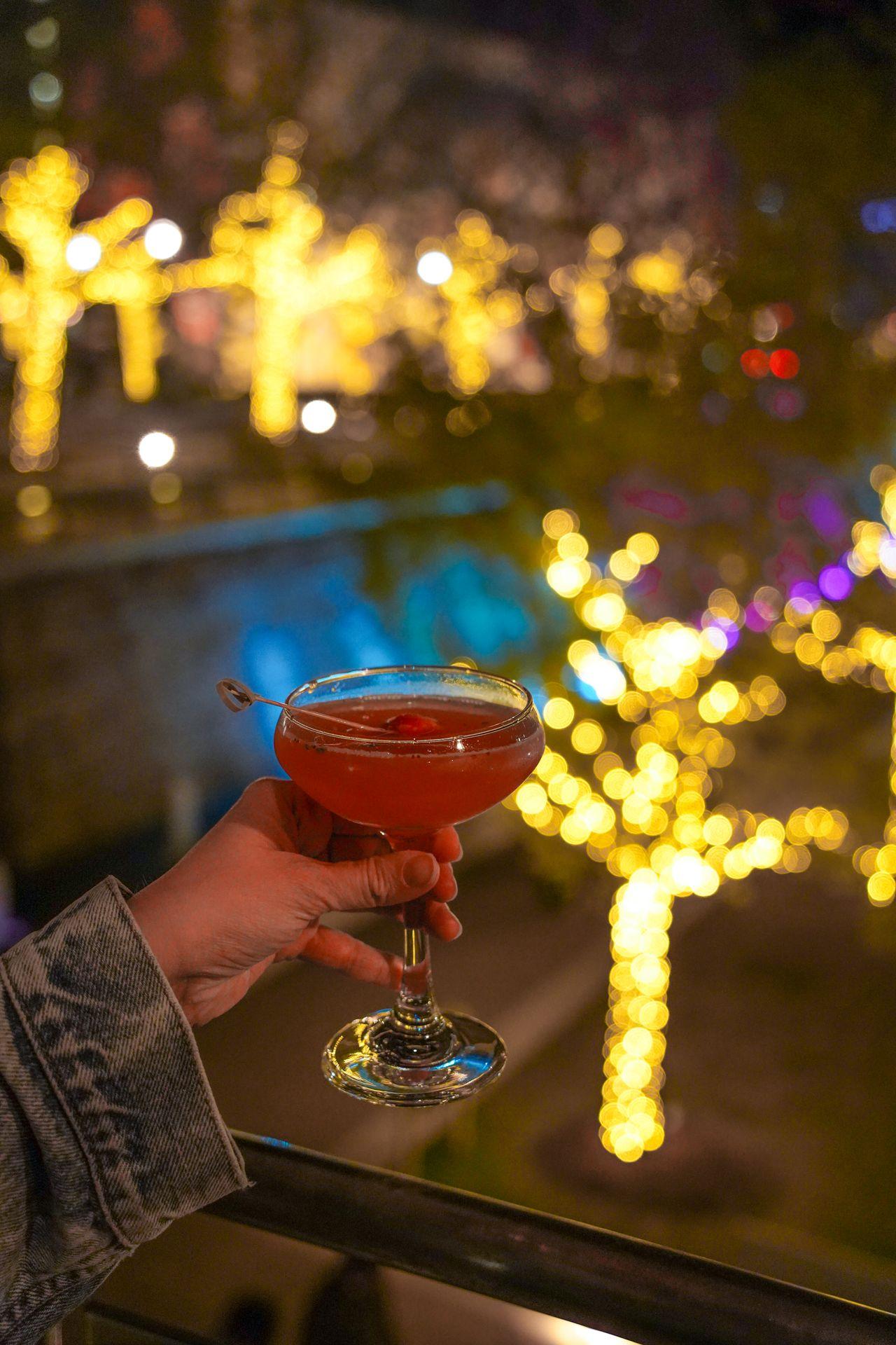 Holding up a strawberry cocktail while looking down at the view of The Woodlands Waterway Square