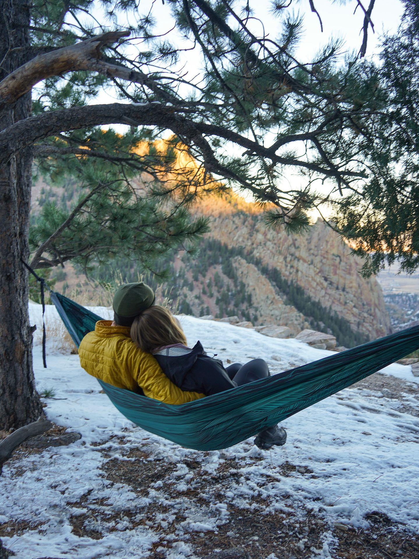 Lydia and her husband sitting on an hammock admiring a view. There is snow on the ground