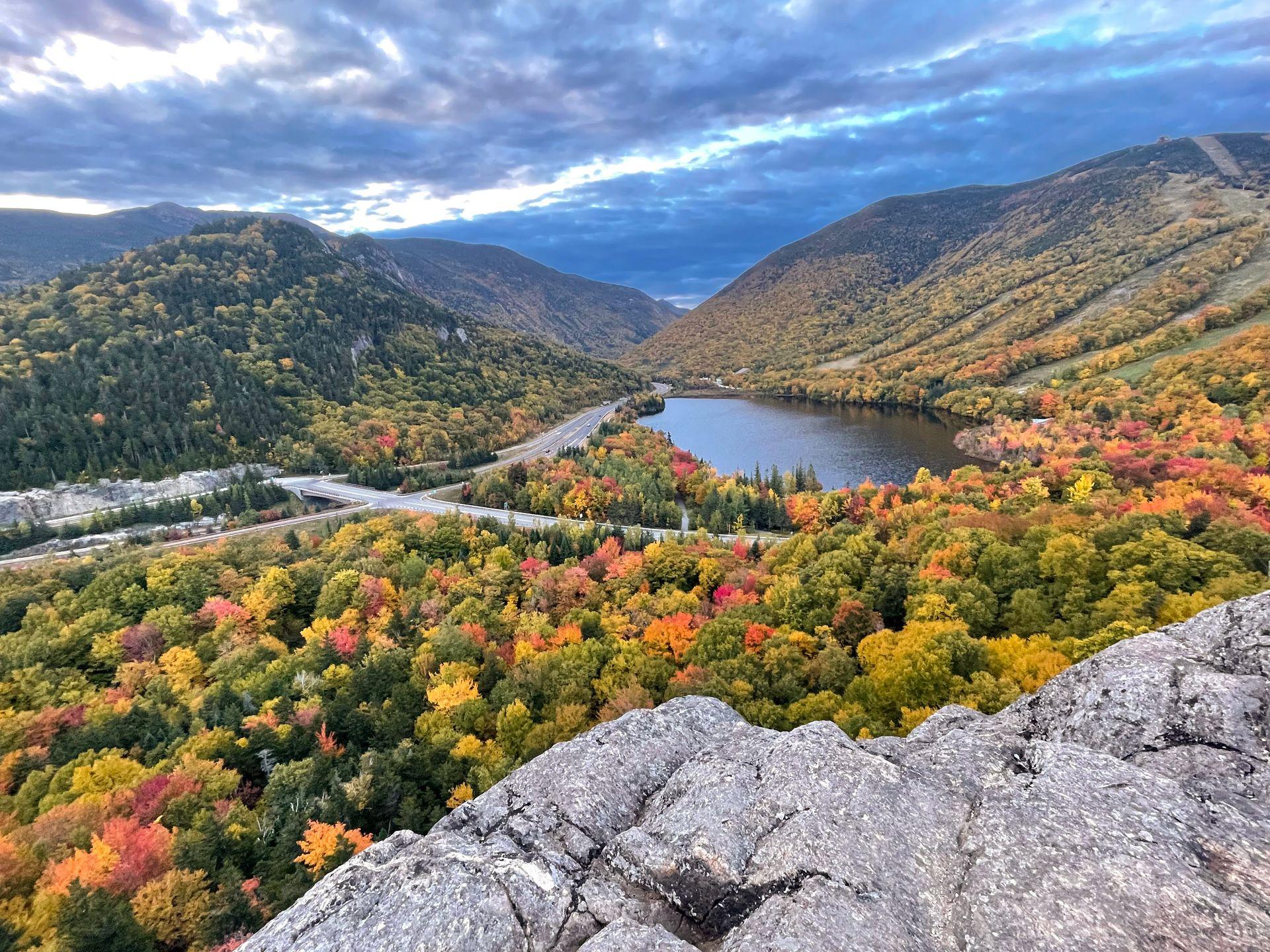 A small lake seen from above, surrounded by hills full of colorful foliage.