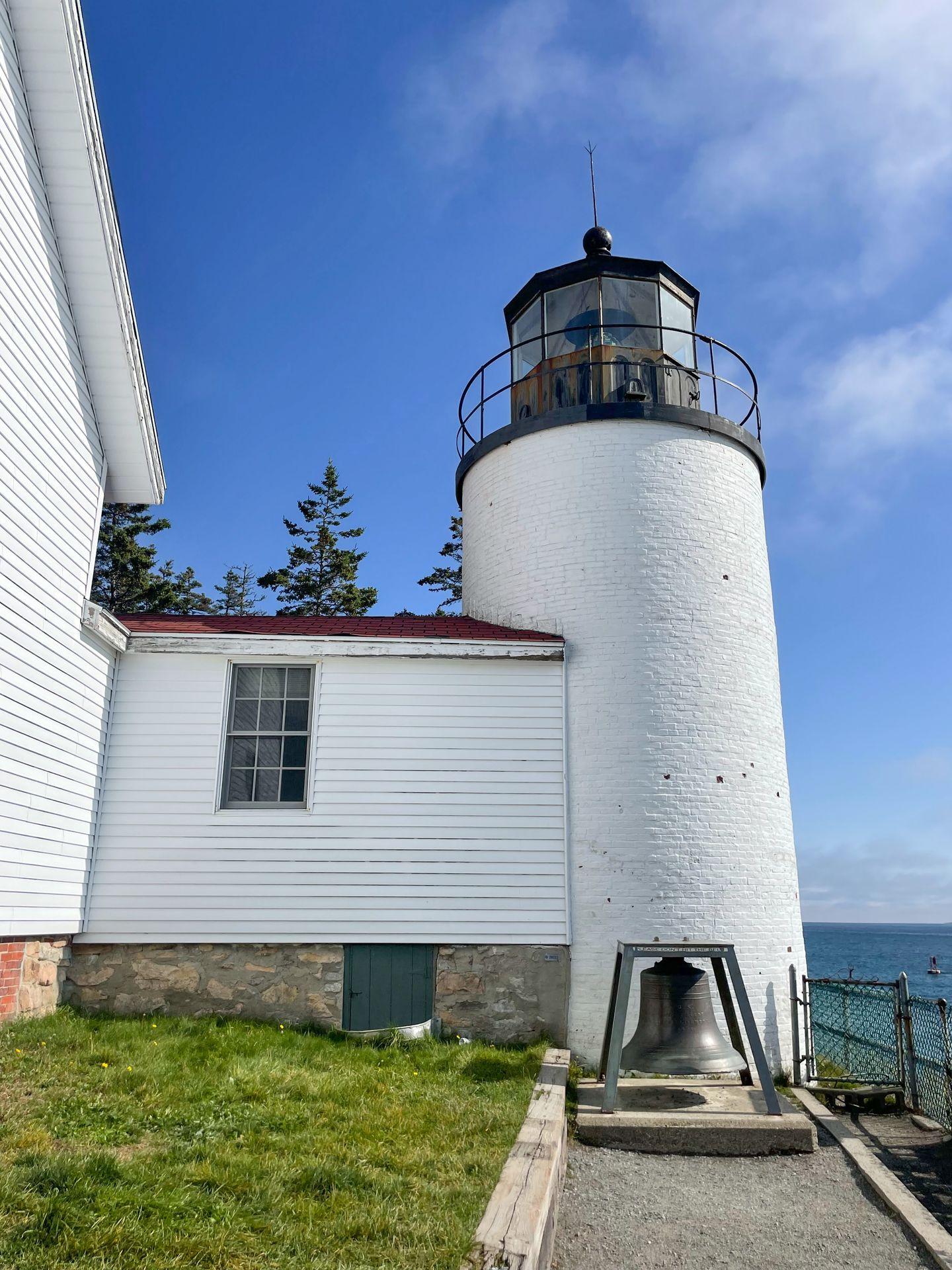 A white lighthouse attached to a white building.