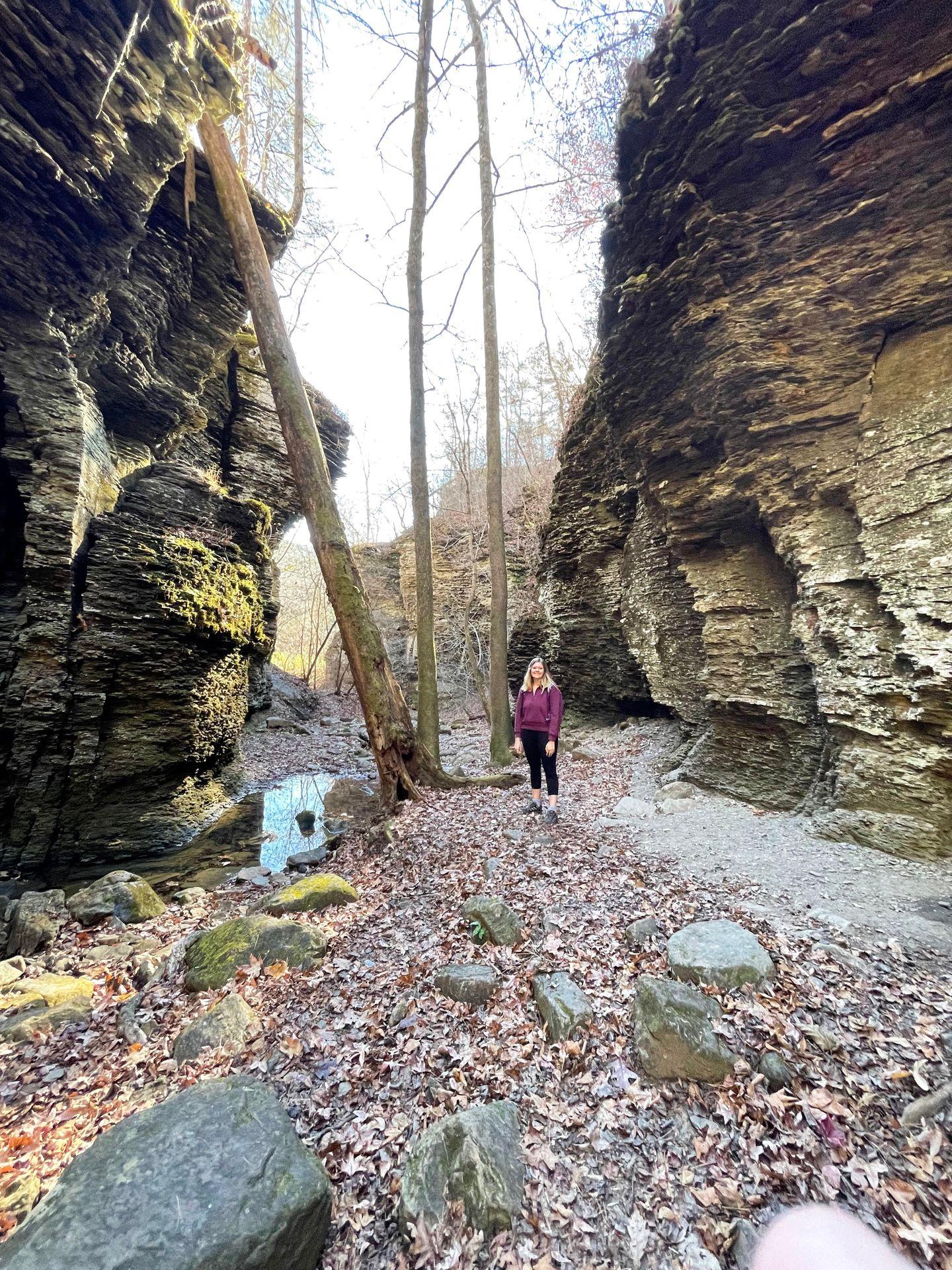 Lydia stands next to the rocky walls that lead into Fuzzy Butt Falls.