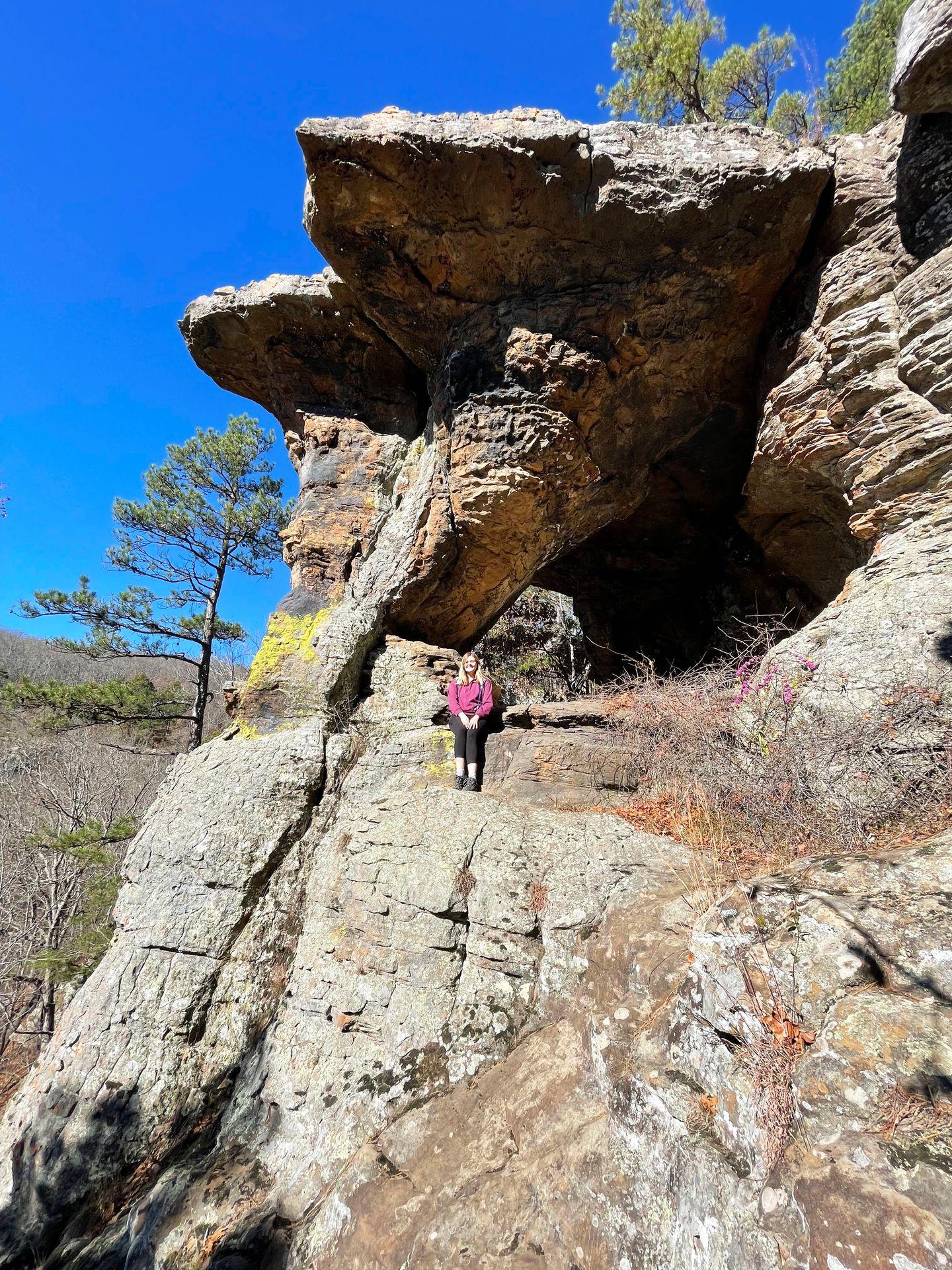 Lydia sits on a rock with the pedestal rocks raising up behind her.