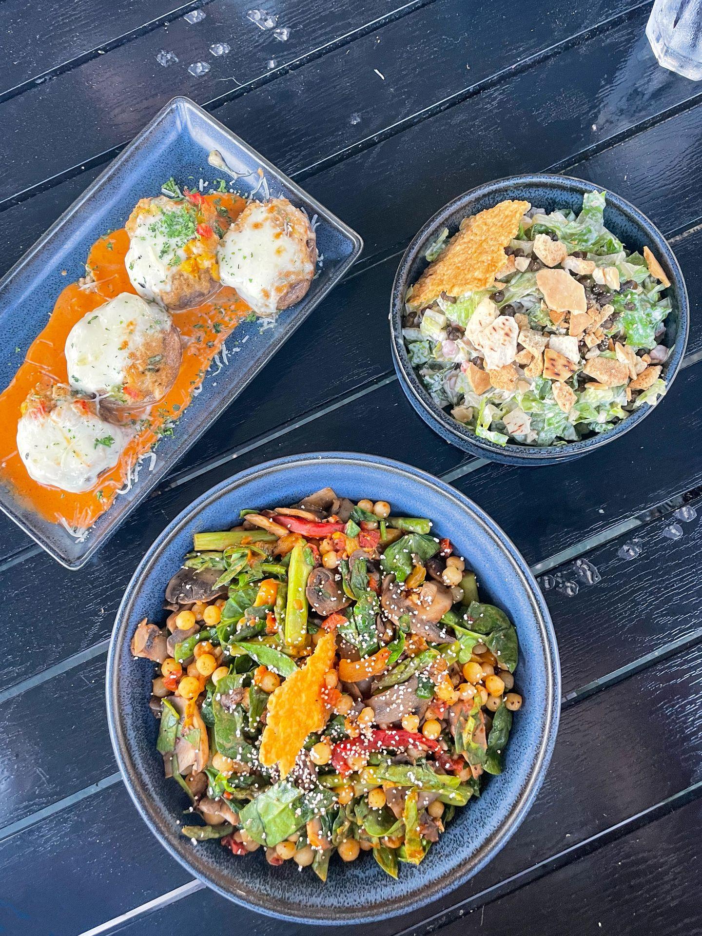 Looking down at a salad, a grain bowl and stuffed mushrooms from JW's Patio