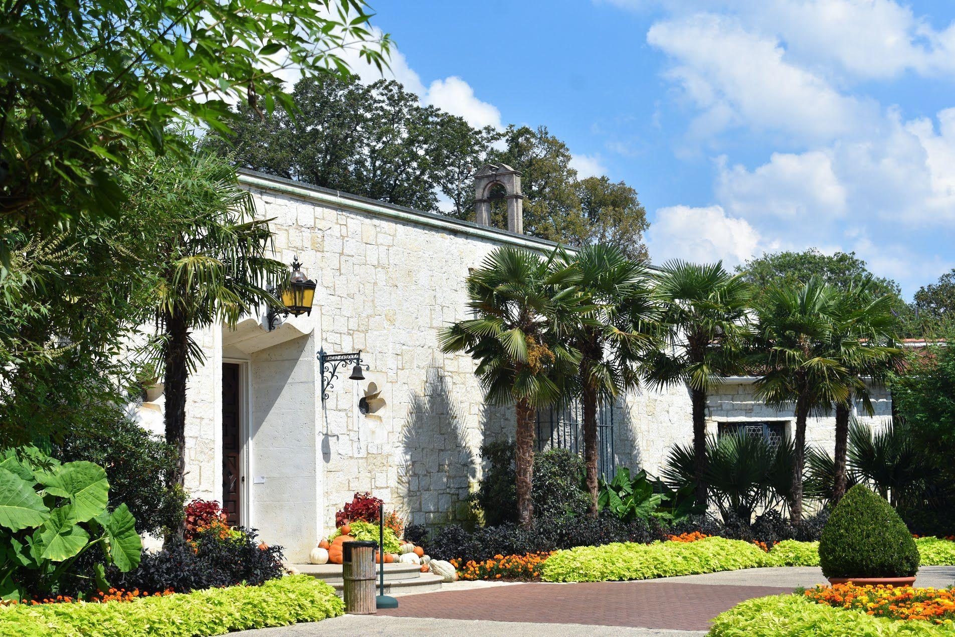 A white mountain with palm trees and flowers in front of it at the Dallas Arboretum