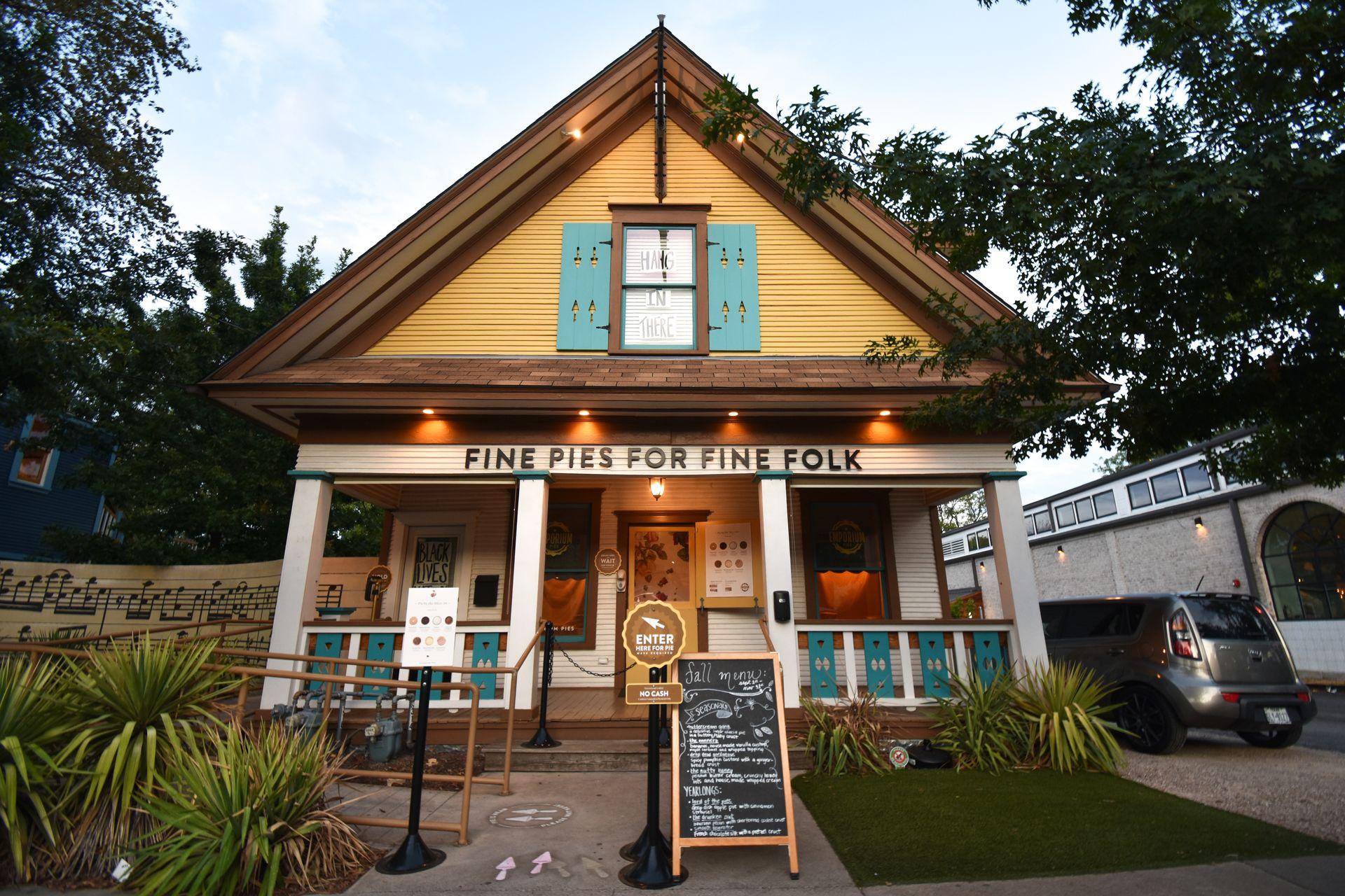 A yellow building with blue shutters that reads "Fine Pies for fine folk"