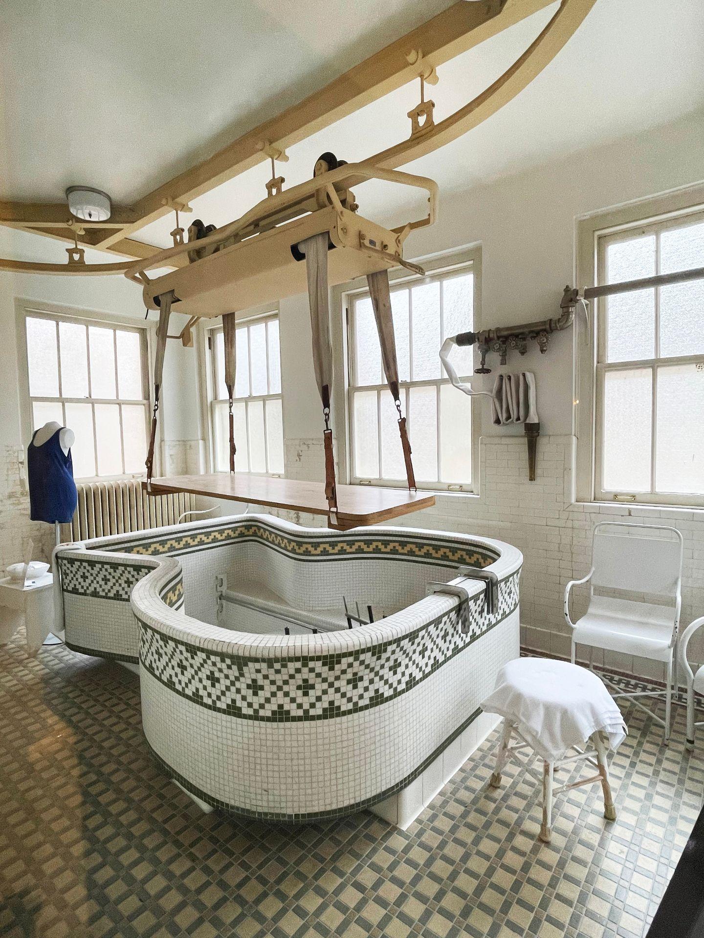 A porcelian tub with a device hanging over it. This was used for medical procedures.