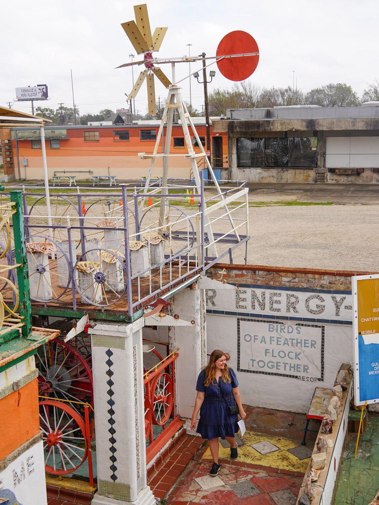 Lydia wanting through The Orange Show Monument. Behind her, the wall reads: 'Energy. Birds of a feather flock together.'