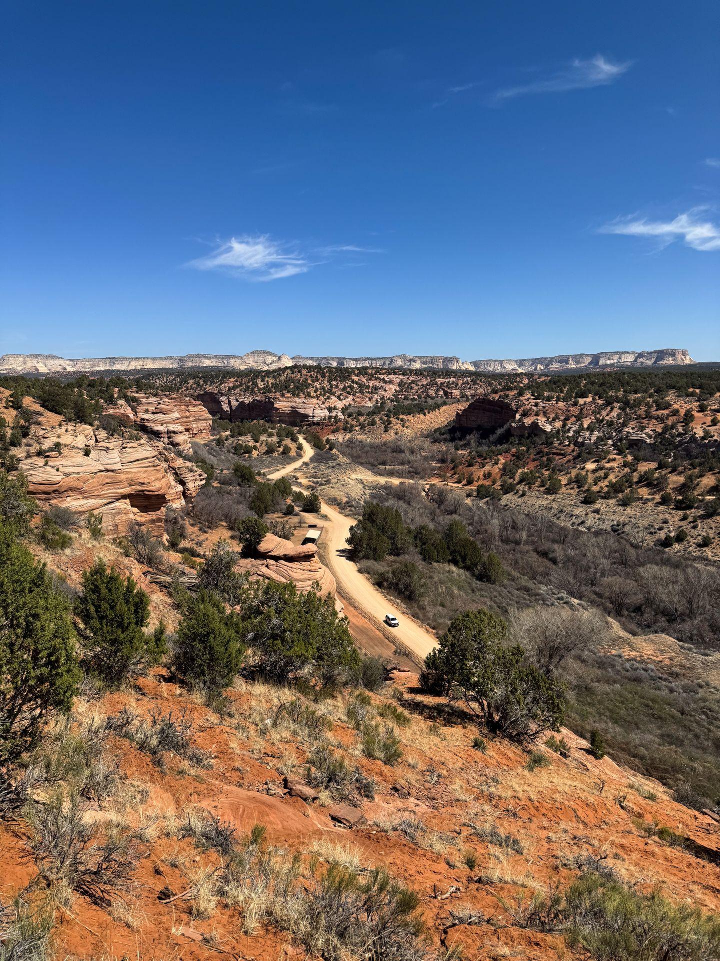 The view of Best Friends Animal Sanctuary from their restaurant. There are red rocks in the distance and a dirt road below.