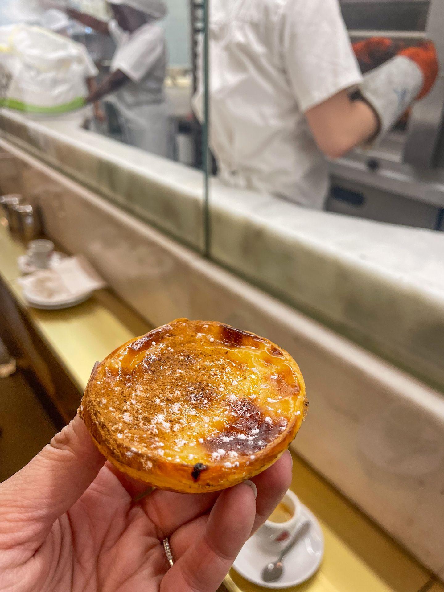 Holding up a pastel de nata inside of Manteigaria