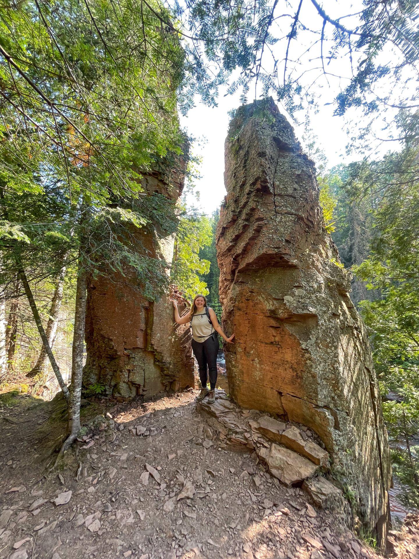 Lydia standing between two large rocks that seem to stick straight out of the ground.