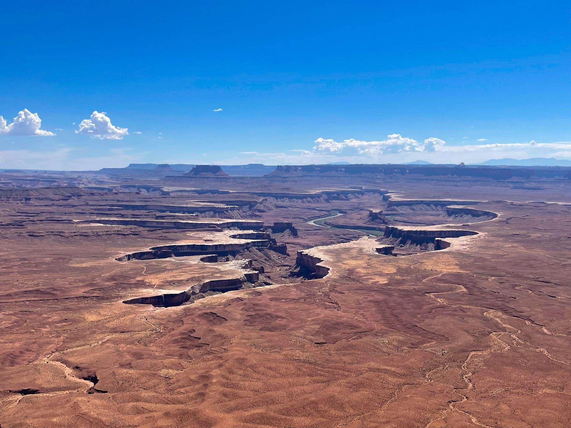 Looking out at an area of the canyon that has been carved with water. The rim of the canyon is white and you can see the river at the bottom