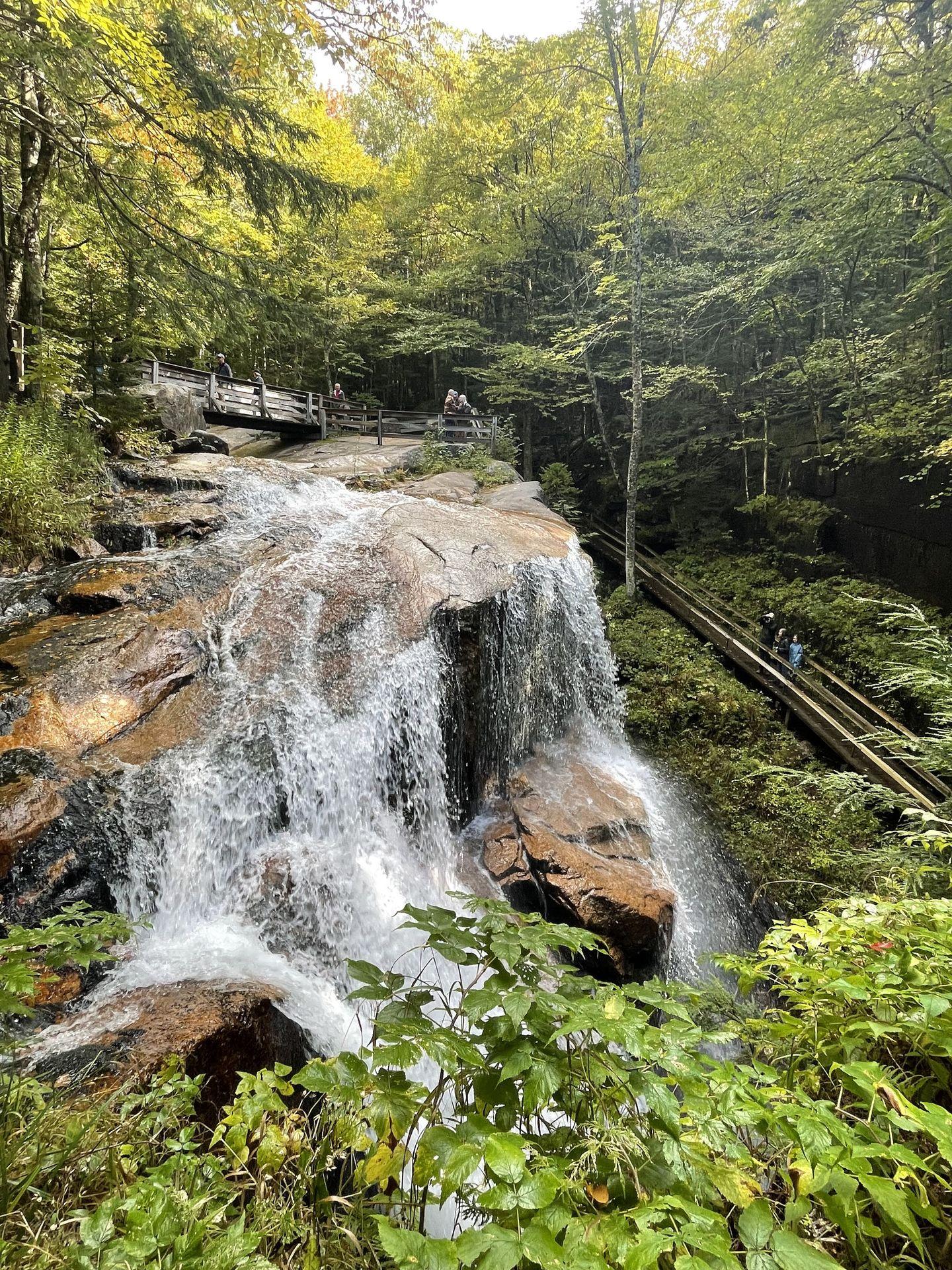 A tall waterfall with trails above it and to the side.