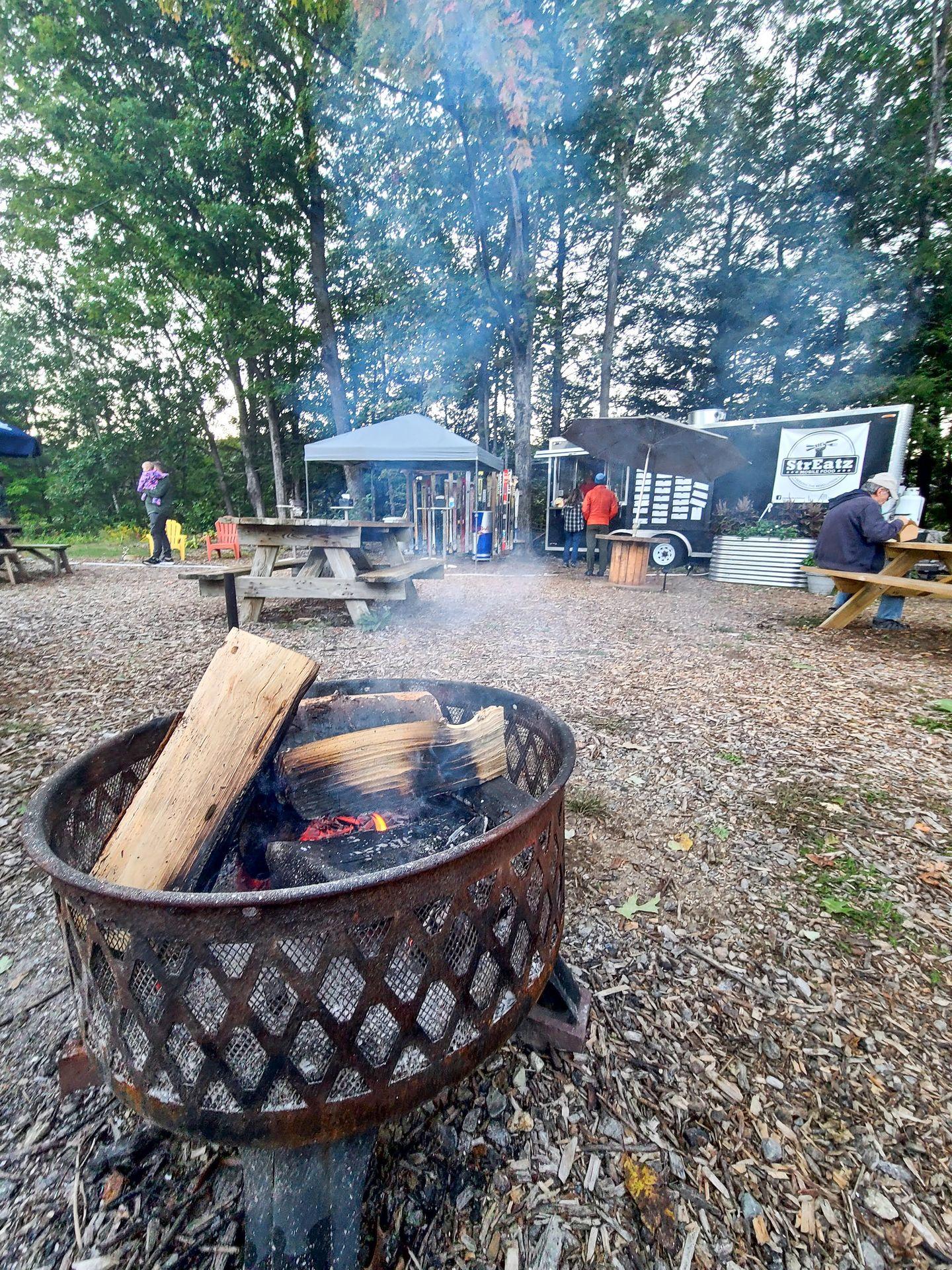 The outside trailer for StrEatz with a fire pit burning a fire to keep people who are waiting warm.