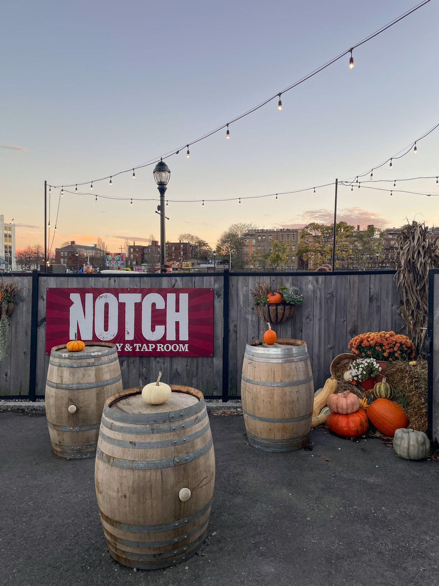 The outdoor patio space at Notch Brewing at sunset. There are barrels and pumpkins out as fall decor