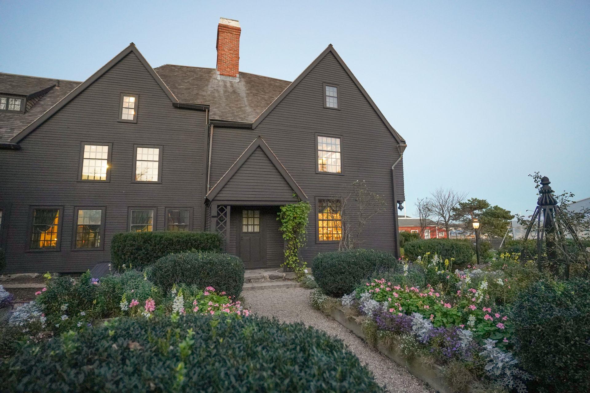 A gray house with a yard full of colorful flowers.