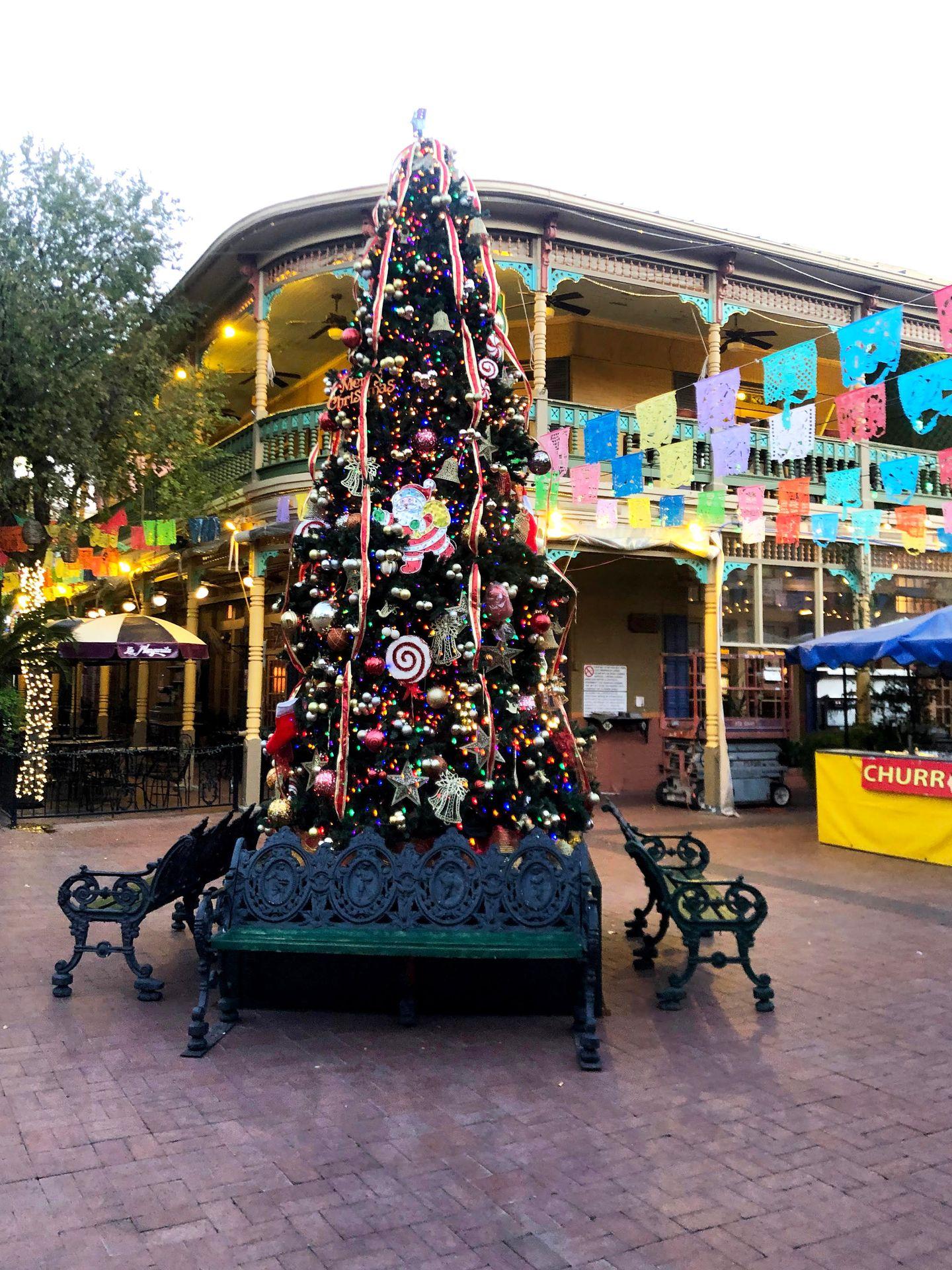 A Christmas tree with colorful flags in the background.