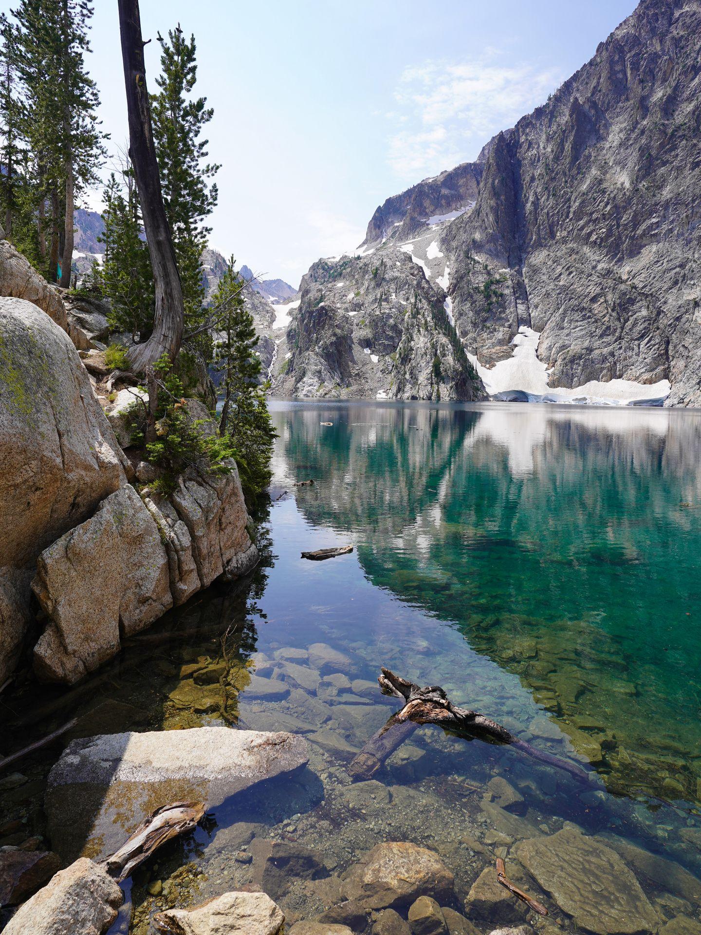 Several logs in the water at Goat Lake. A giant boulder sits next to the water.