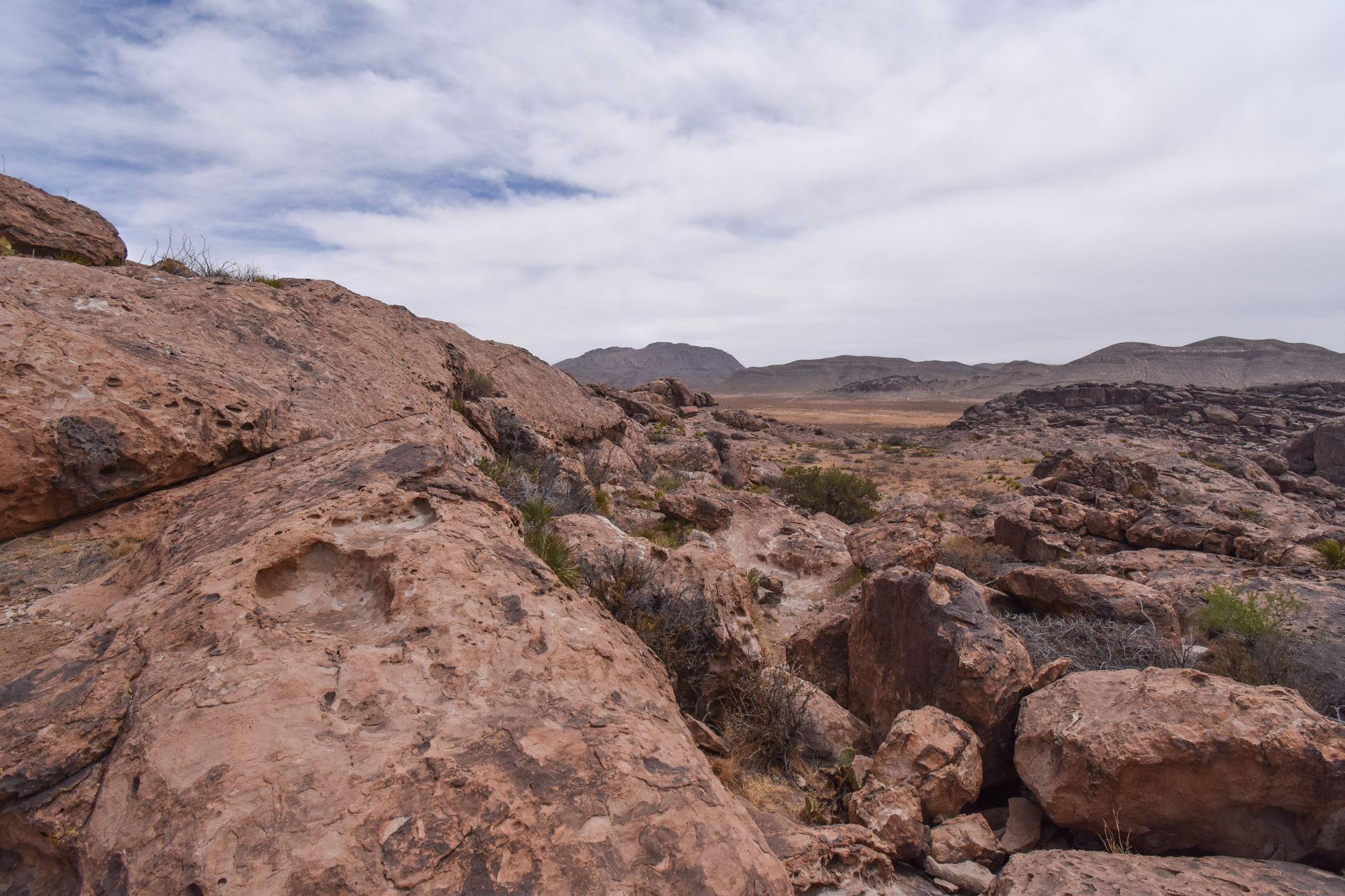 Standing up on top of rocks and looking at a landscape with tan rocks and boulders
