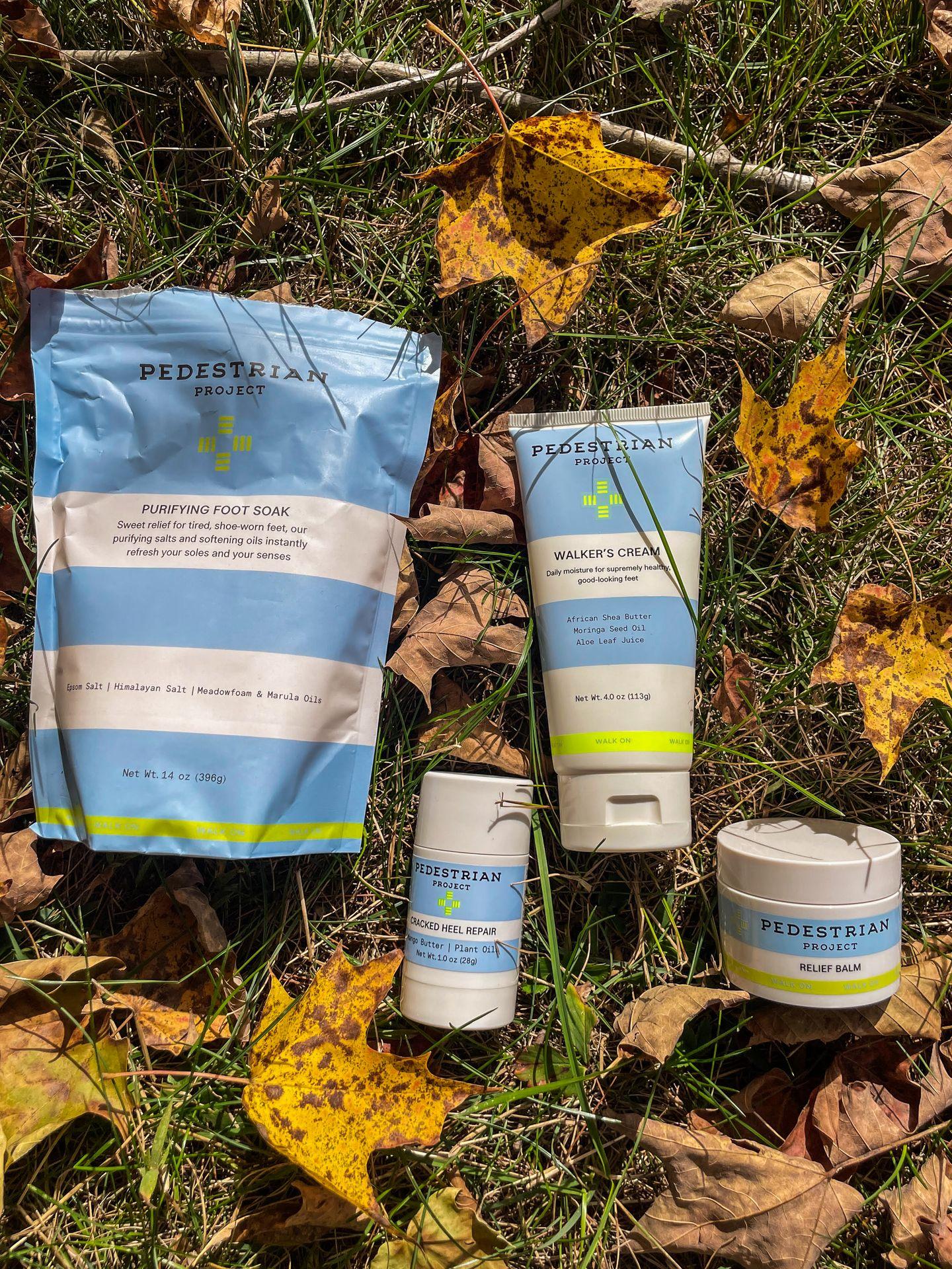 Four Pedestrian Project products placed among dry leaves in grass.