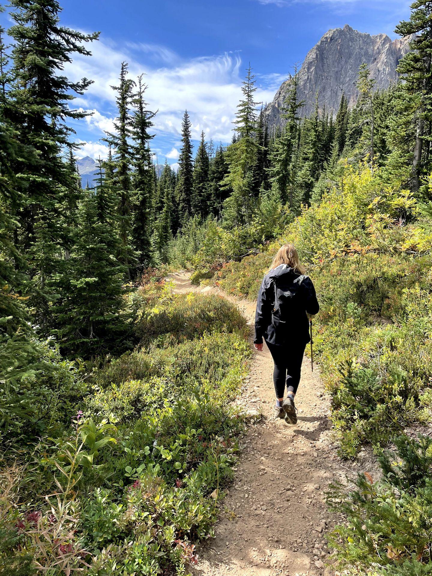 Lydia hiking on a trail in Washington State using a trekking pole.