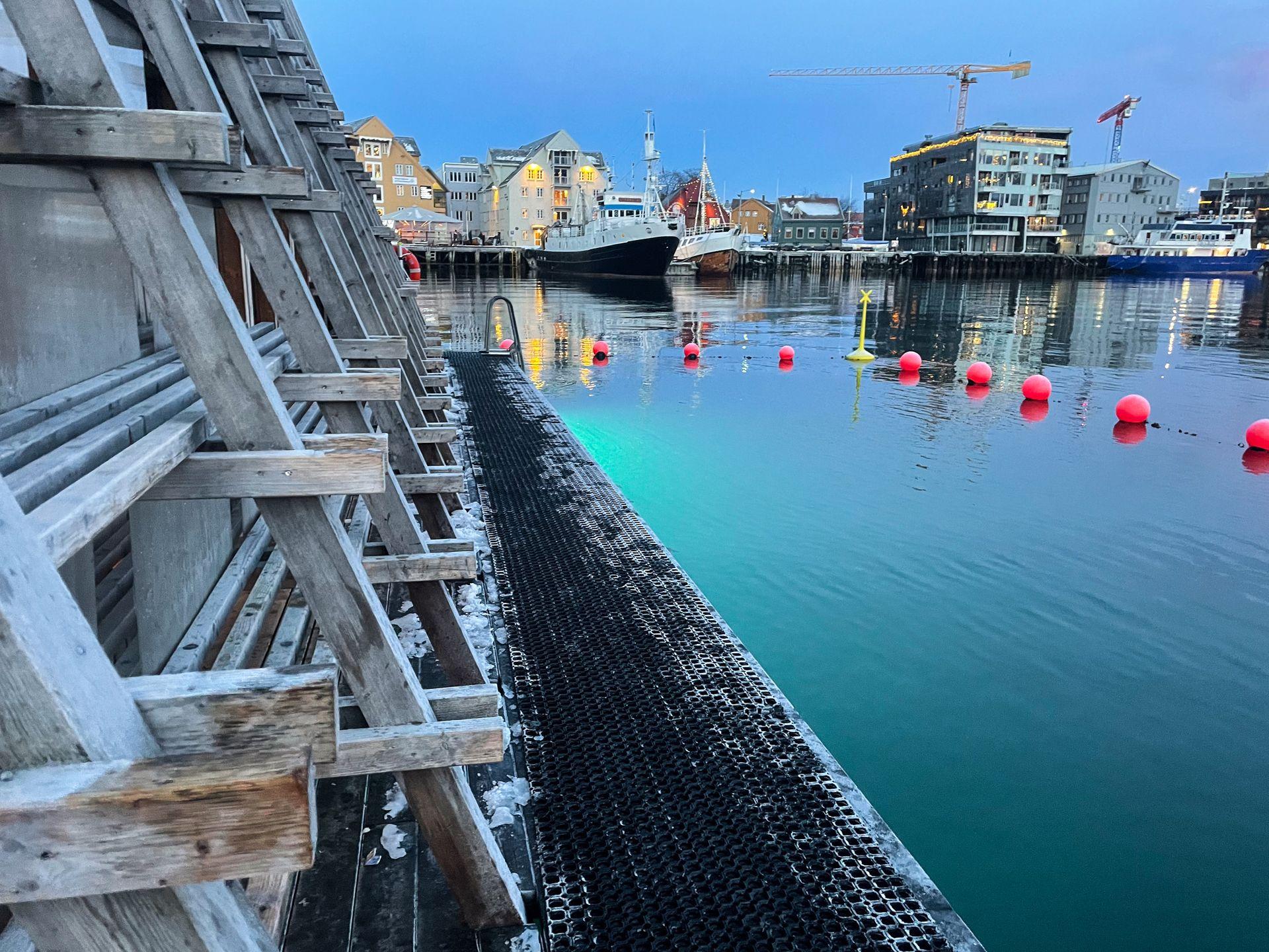A wooden structure with angled walls floating in the harbor.