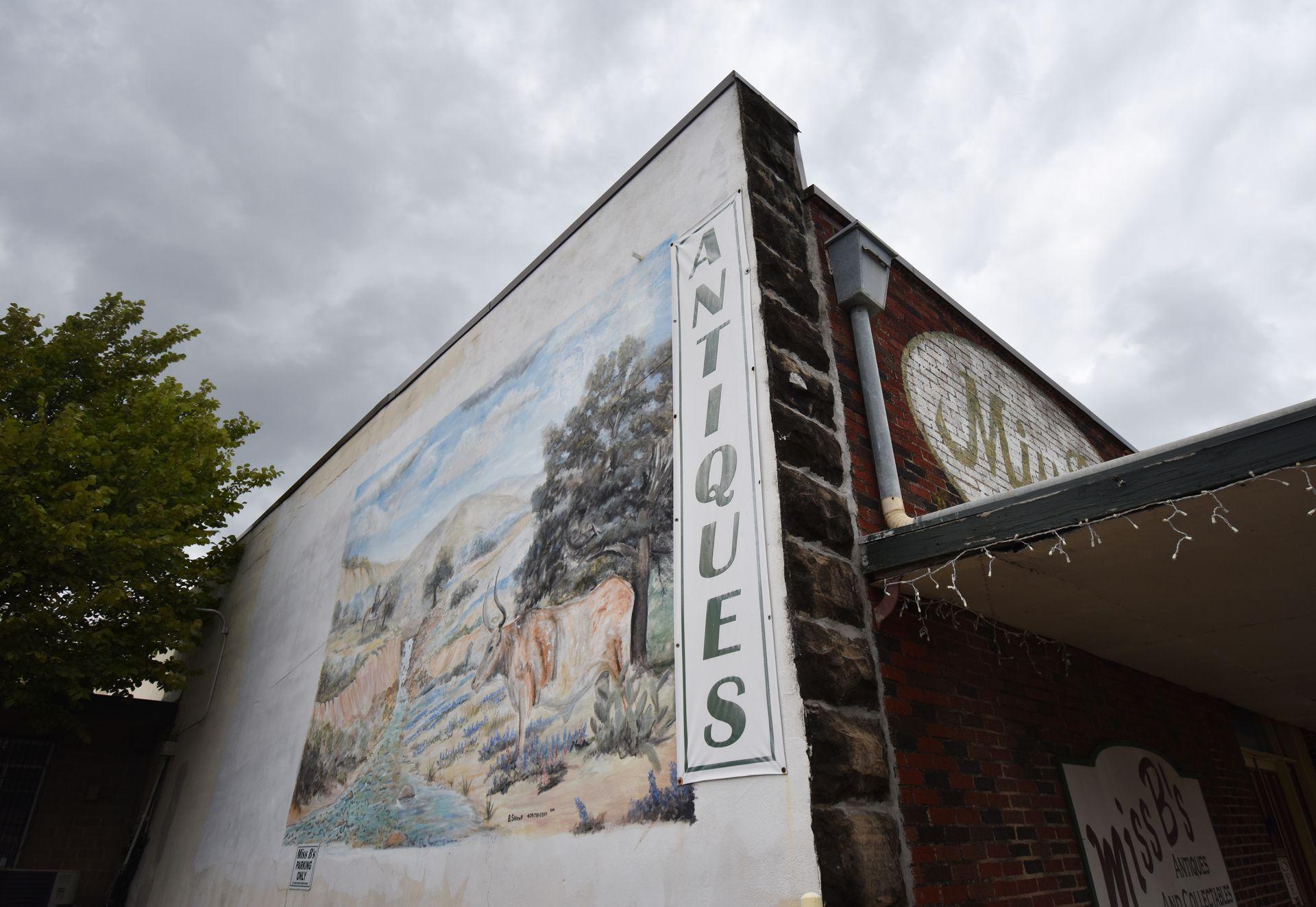 A mural and the word "Antiques" on the side of a building in Weatherford.